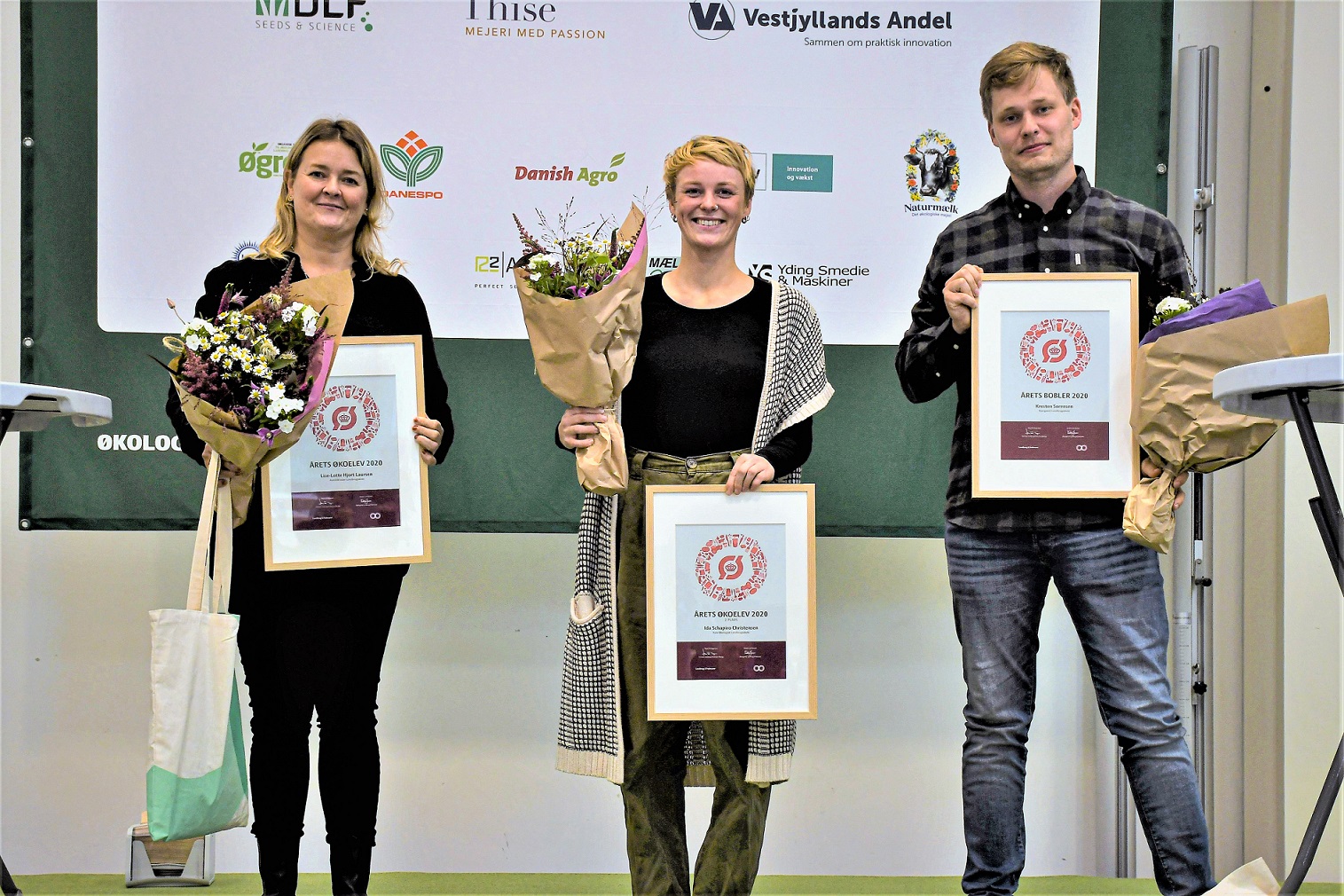 Tre vindere står og fremviser diplom og blomster