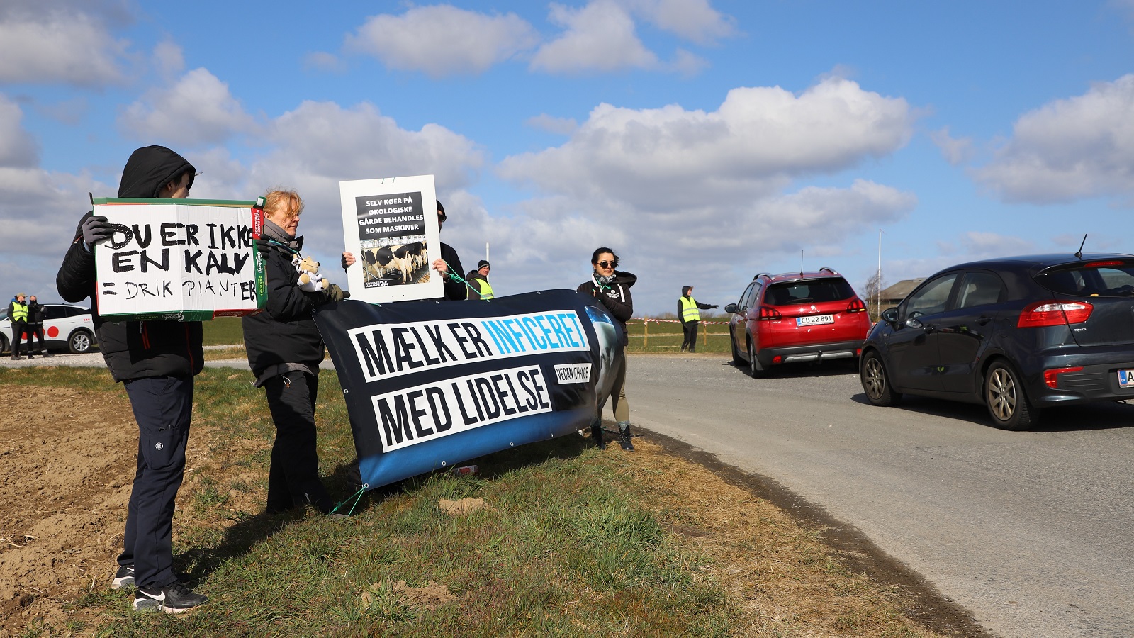 Aktivister fra Dyrenes Alliance med skilte og banner foran indkørslen til Heegaard.