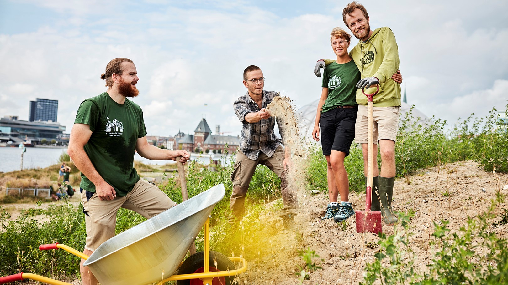 Fire unge står nær Aarhus Havn i arbejdstøj og arbejder på at så blomster og planter