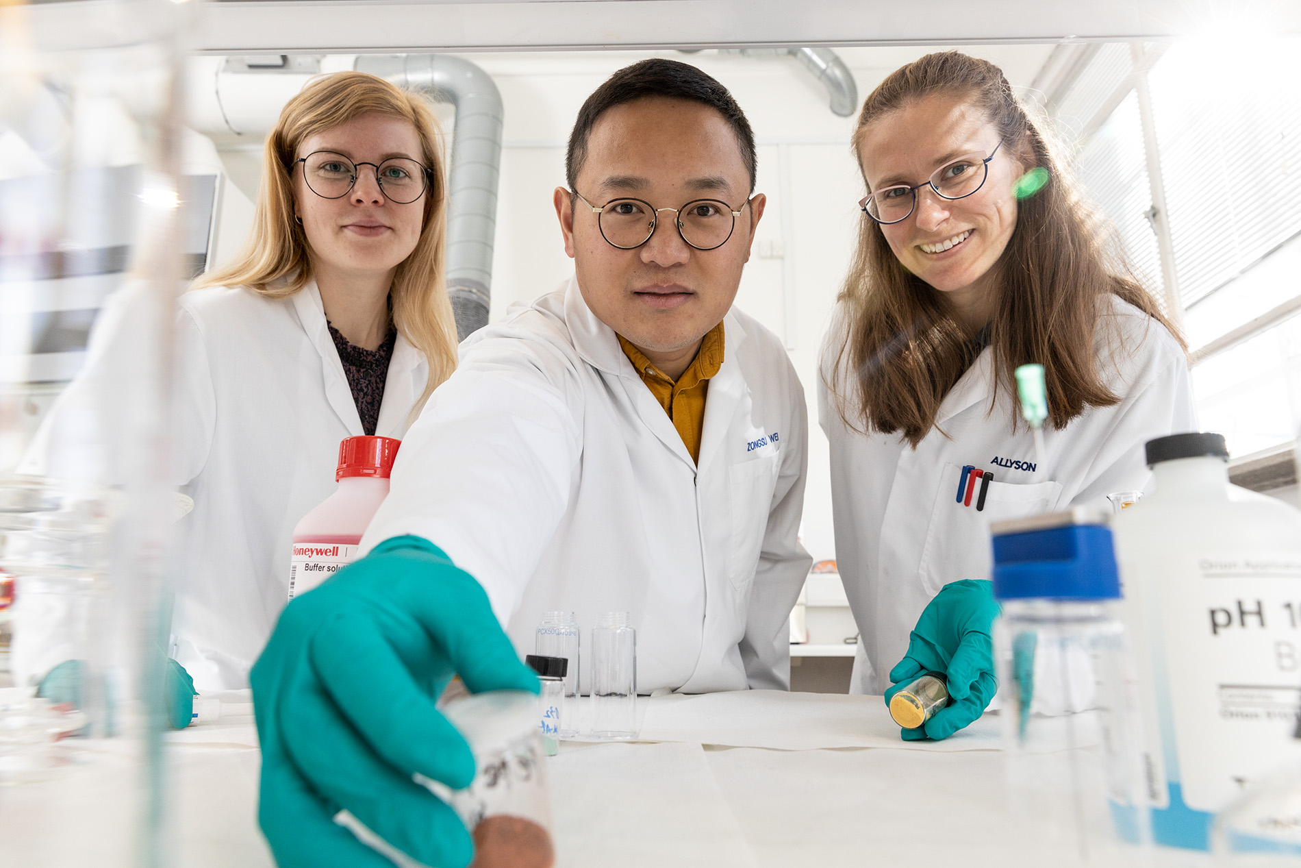 Ph.d.-studerende Charlotte Skjold Qvist Christensen (t.v.), adjunkt Zongsu Wei (midt) og ph.d.-studerende Allyson Leigh Junker står ved siden af hinanden i et laboratorium