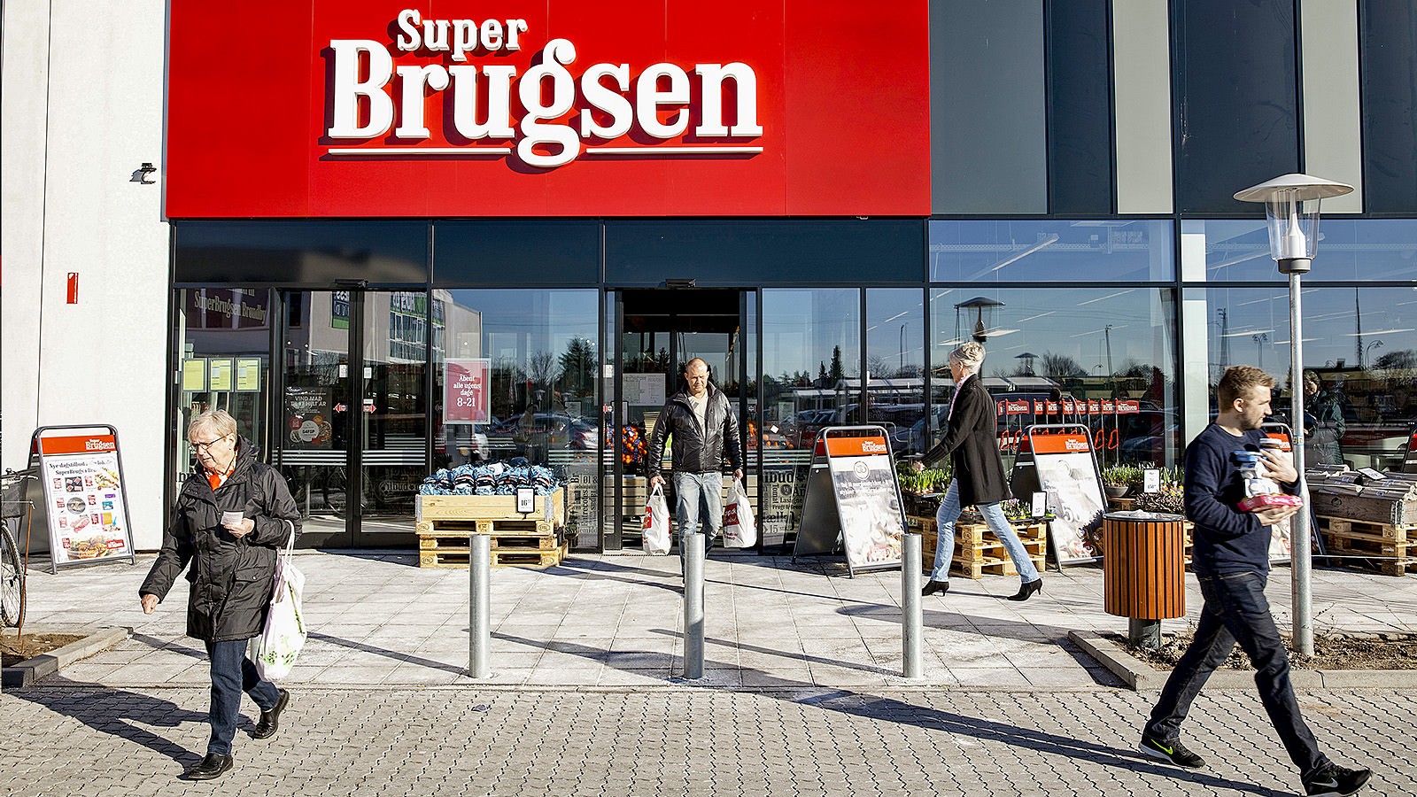 Kunder går ind og ud af en SuperBrugsen-butik.