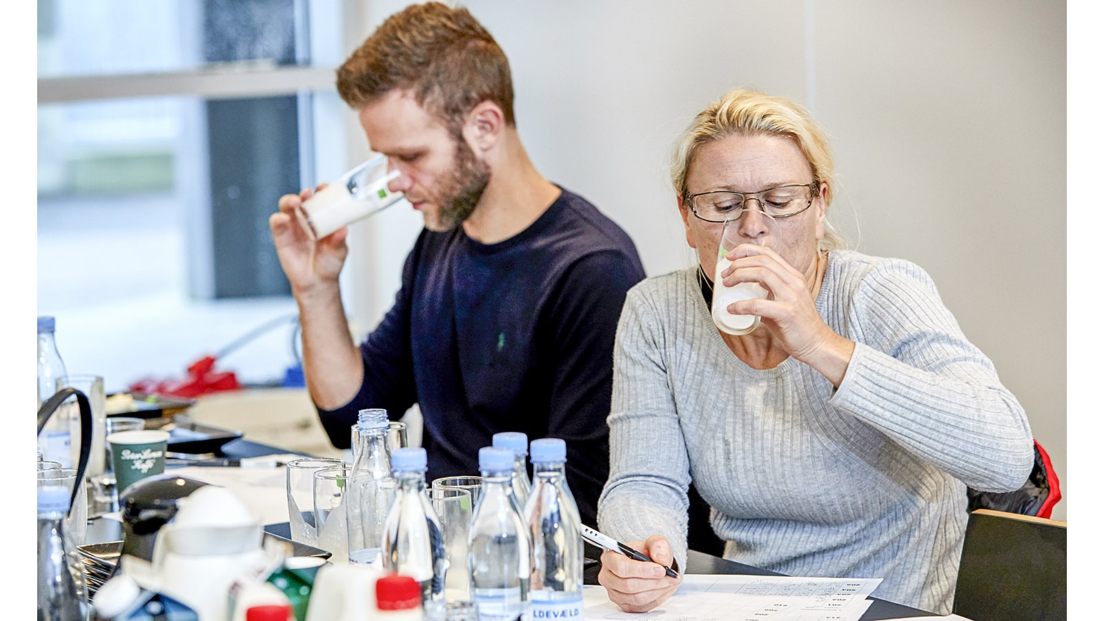 To smagsdommere vurderer et mejeriprodukt og noterer ned på et stykke papir