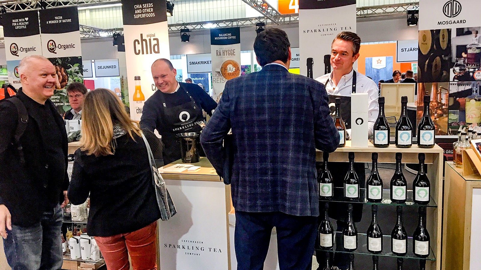 Kunder står ved Copenhagen Sparkling Tea Companys stand på BioFach og taler med firmaejerne Bo Sten Hansen og Jacob Kocemba.