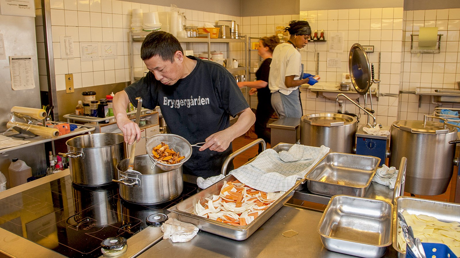 Køkkenpesonale er ved at tilberede mad i et køkken