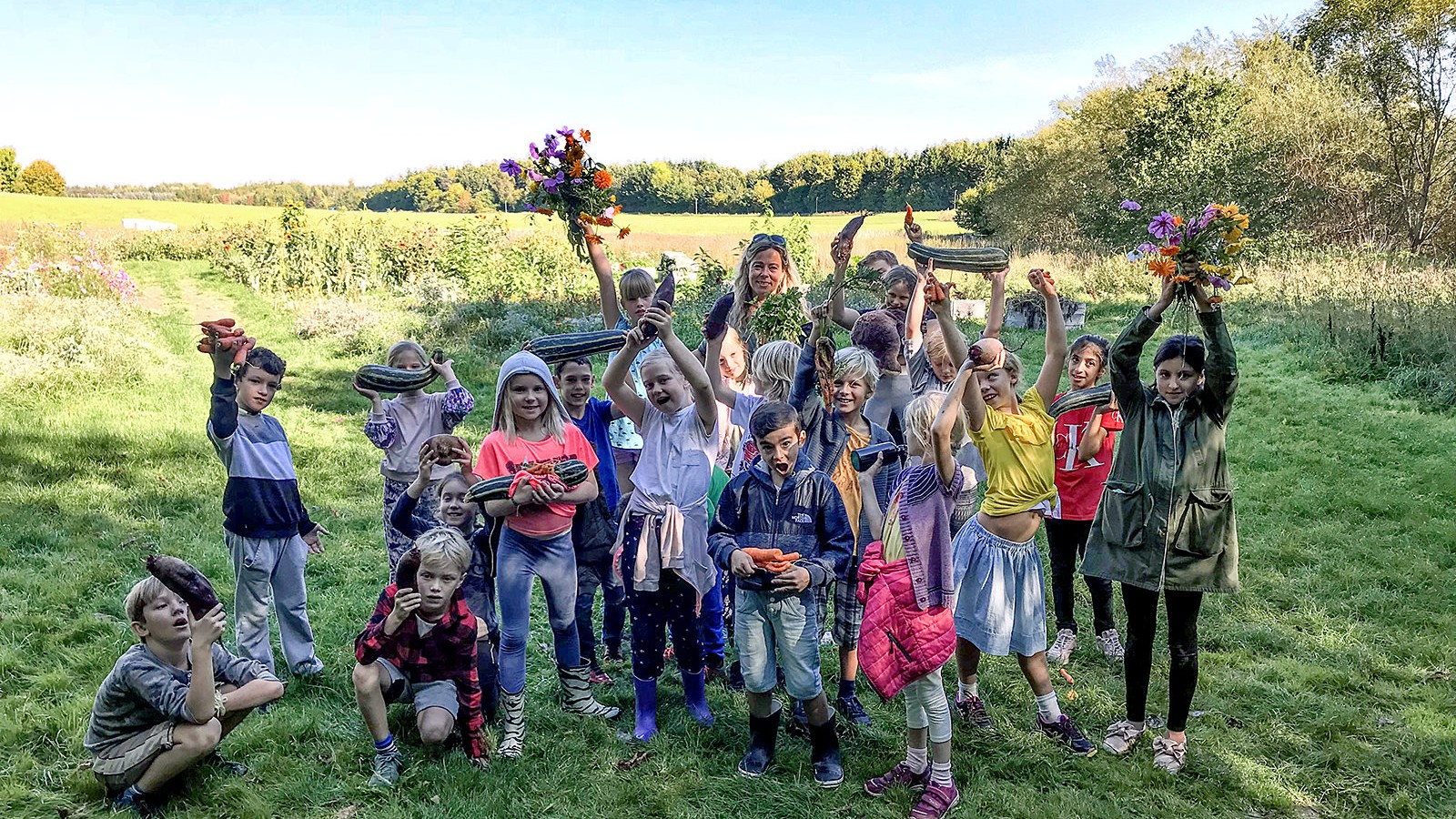 Eleverne fremviser glade dagens høst af grøntsager og blomster