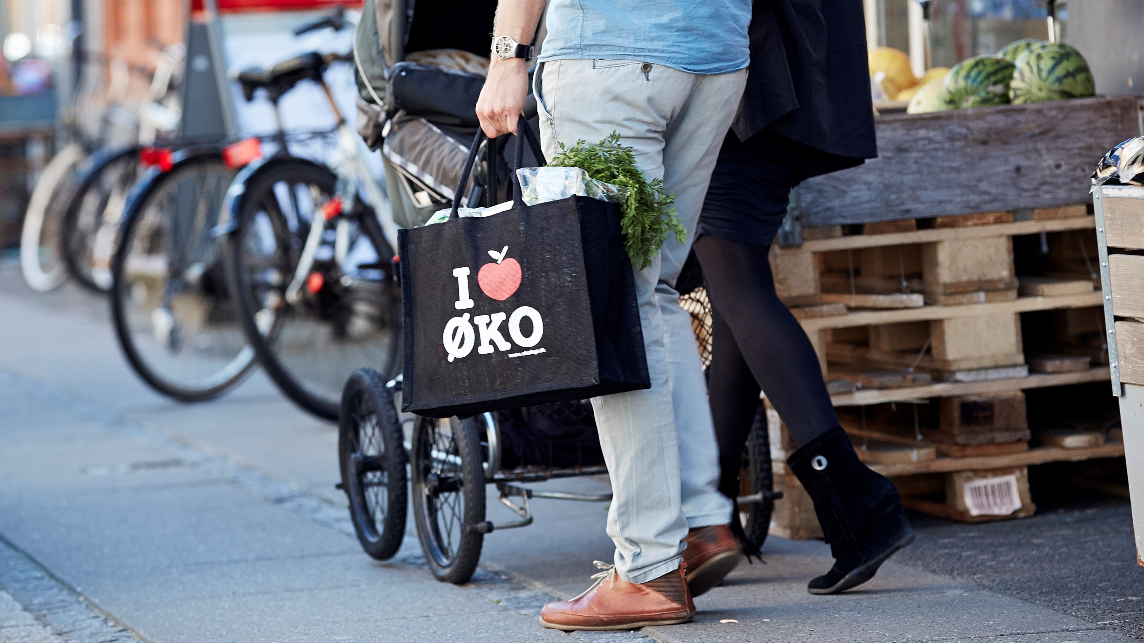 Et par går ud af et supermarked med et indkøbsnet i hånden påtrykt