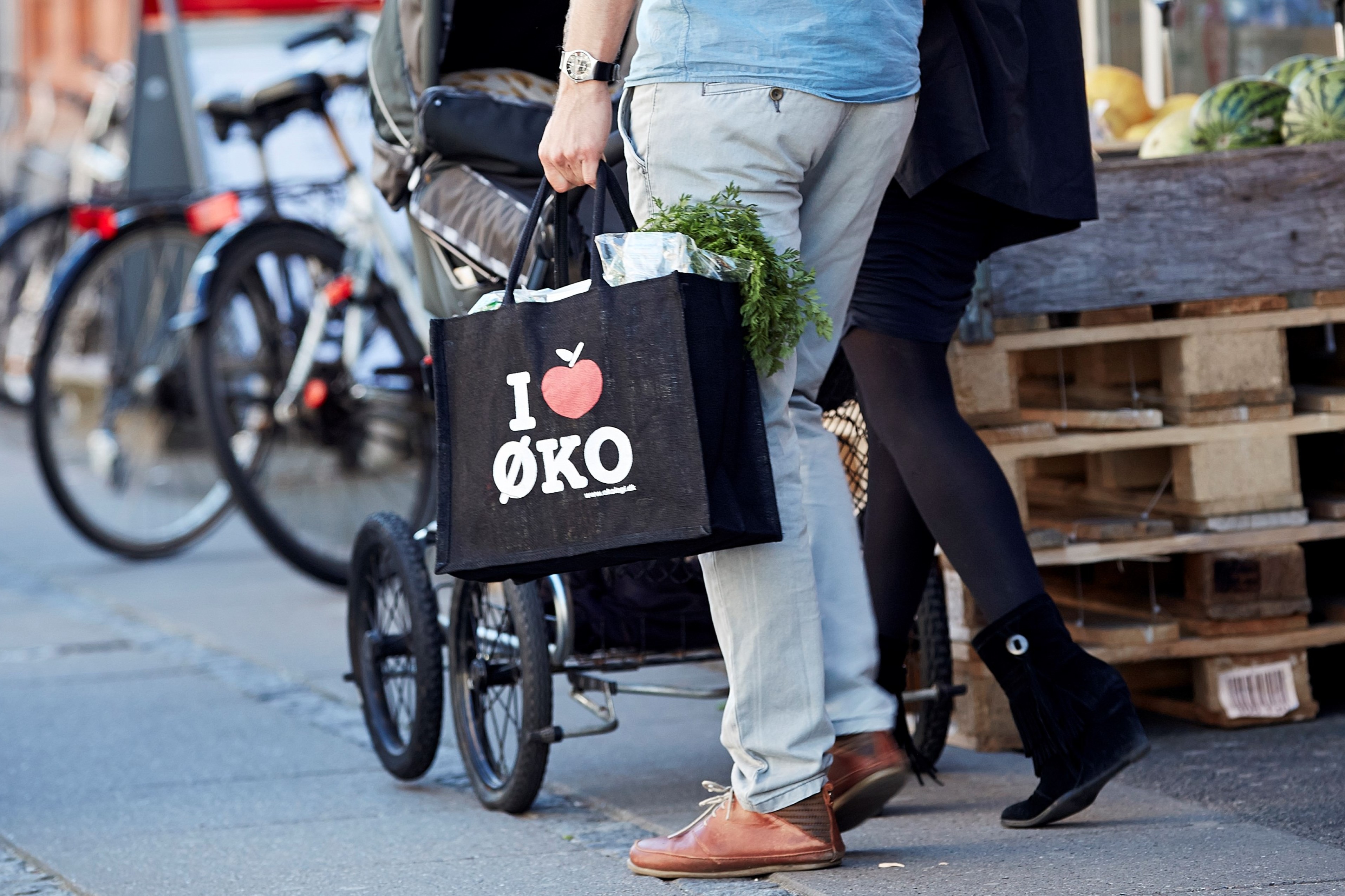 Et par går ud af et supermarked med et indkøbsnet i hånden påtrykt