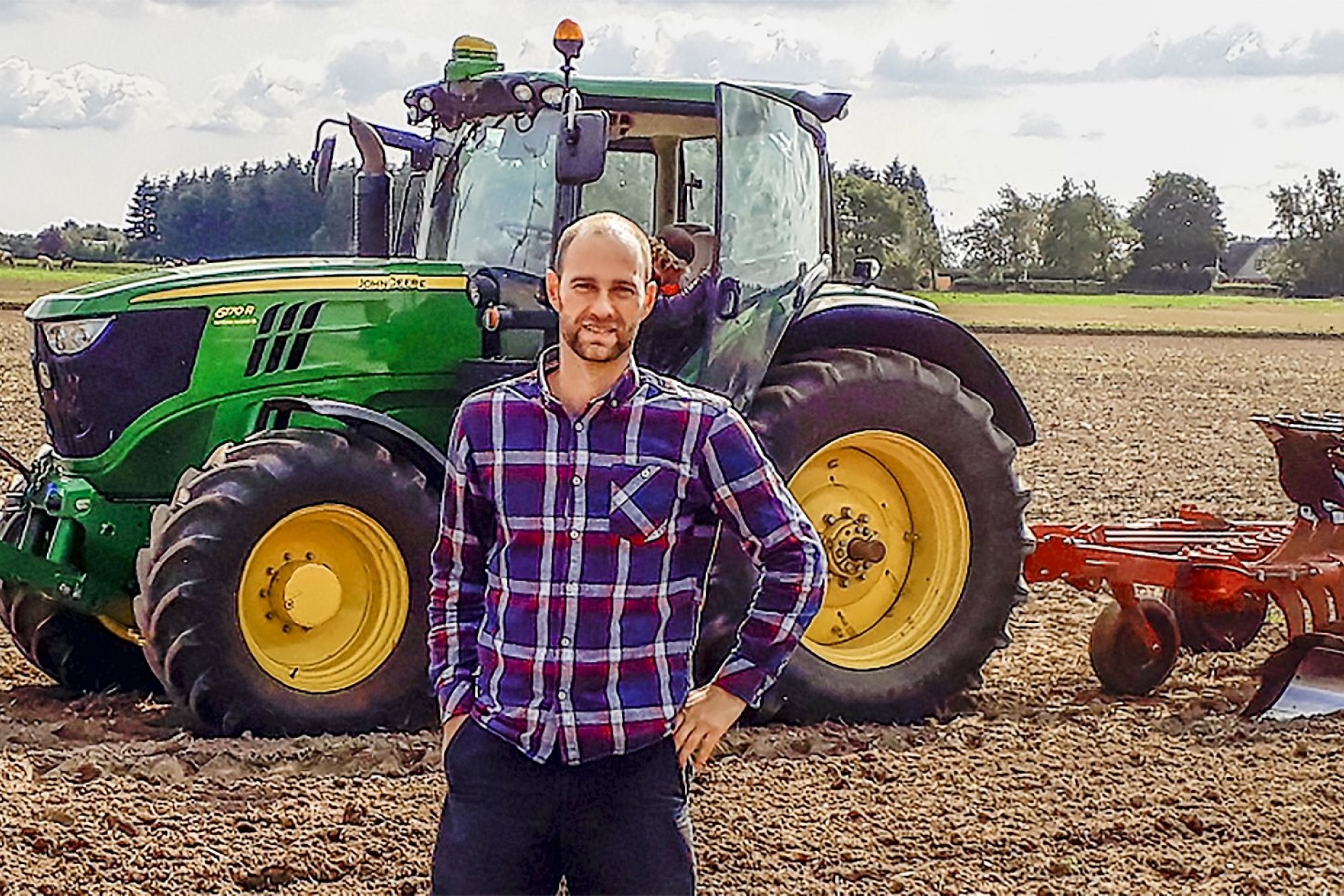 Jonas Høeg står foran en traktor på en mark