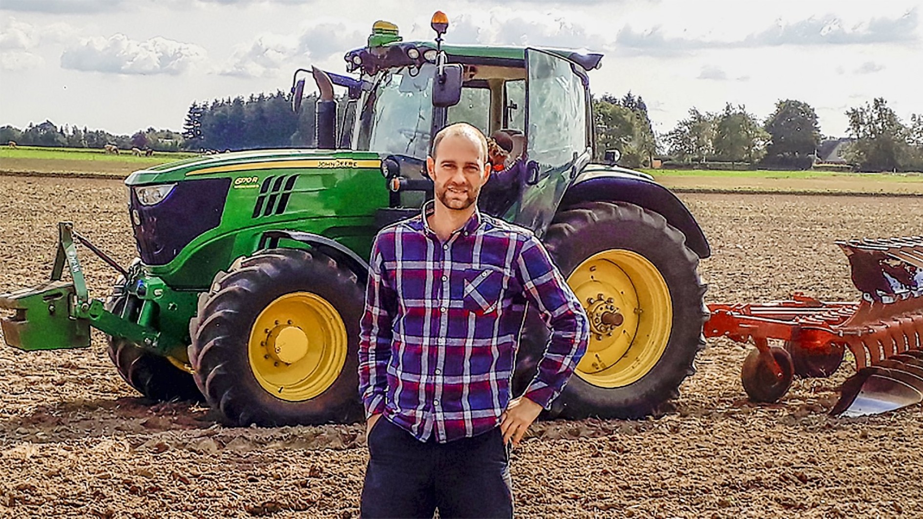 Jonas Høeg står foran en traktor på en mark