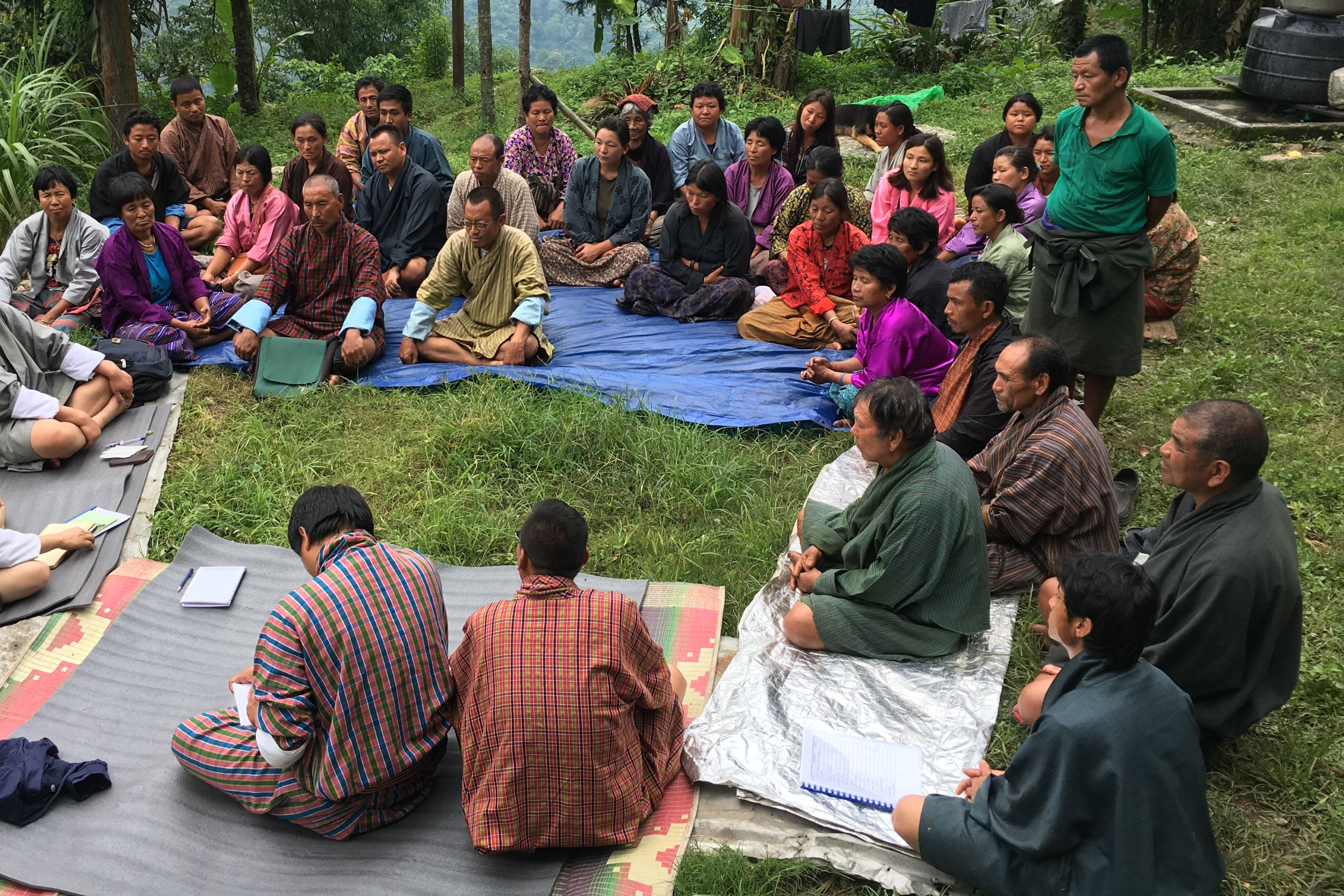 En gruppe bønder sidder i en rundkreds og lytter til en oplægsholder i Bhutan