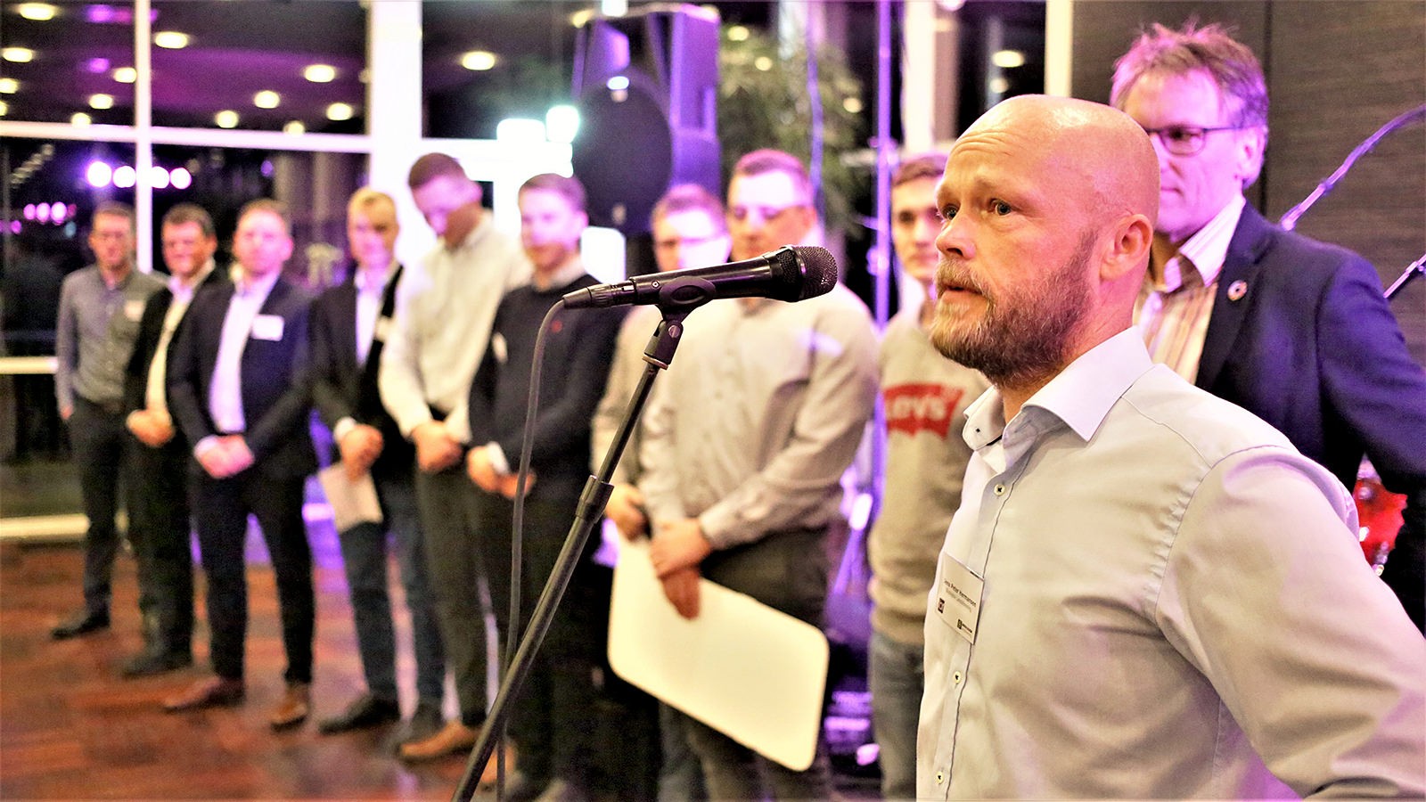 Jens Peter Hermansen taler i en mikrofon - bag ham står vinderne af 'I gang for 1 million' og 'I gang for 2 millioner'