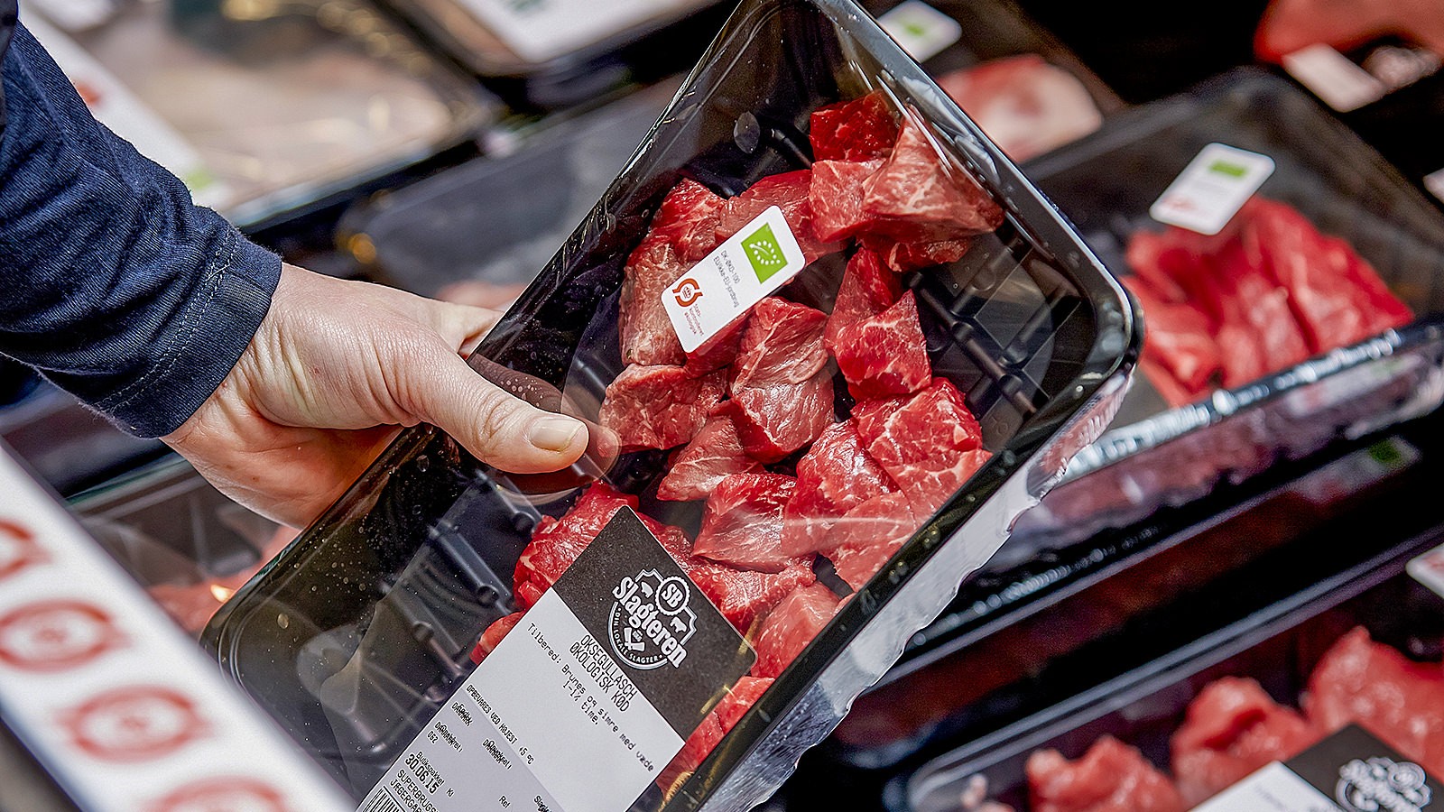 En forbruger tager en pakke oksekød op fra køledisken