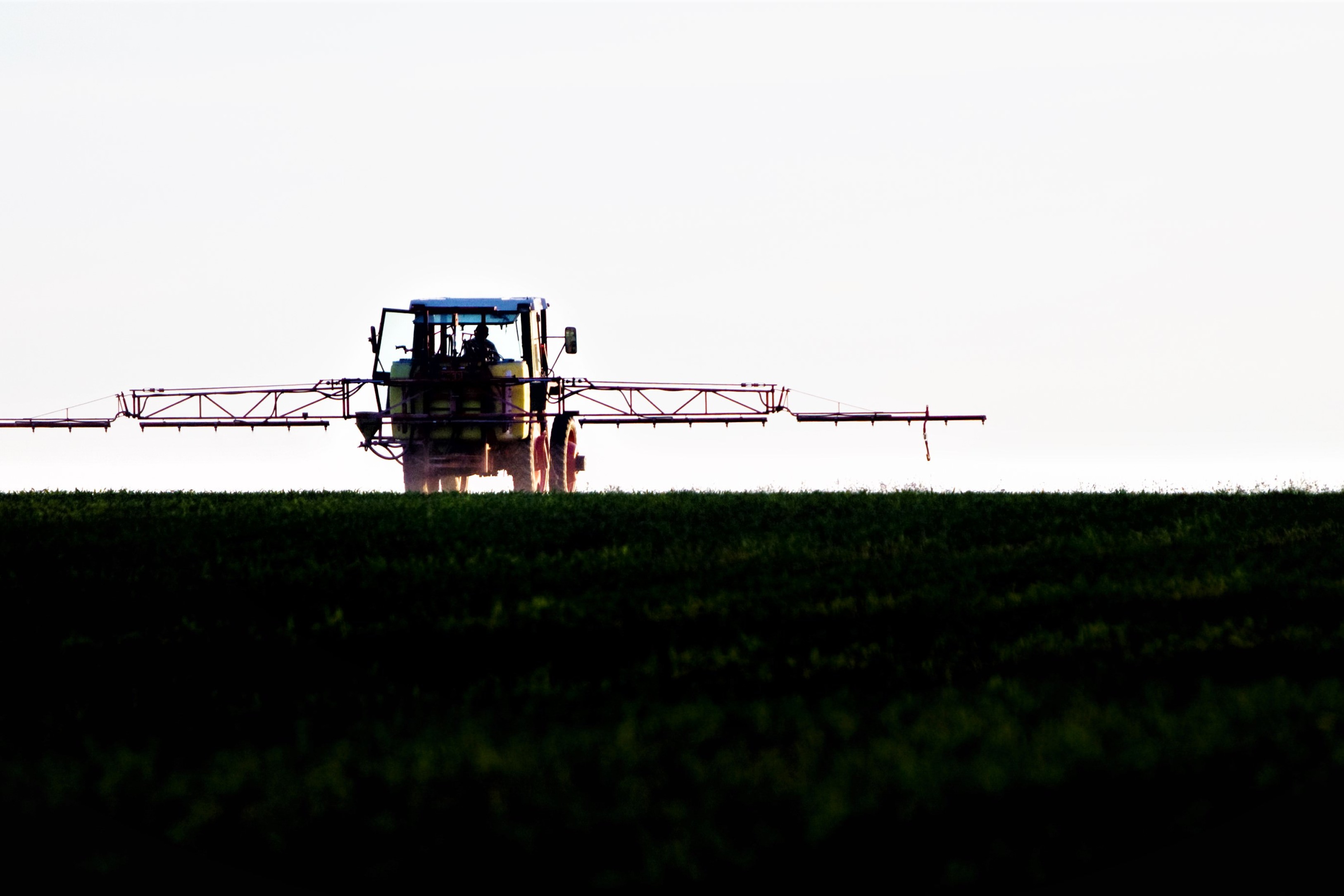 En traktor kører over marken med en sprøjte