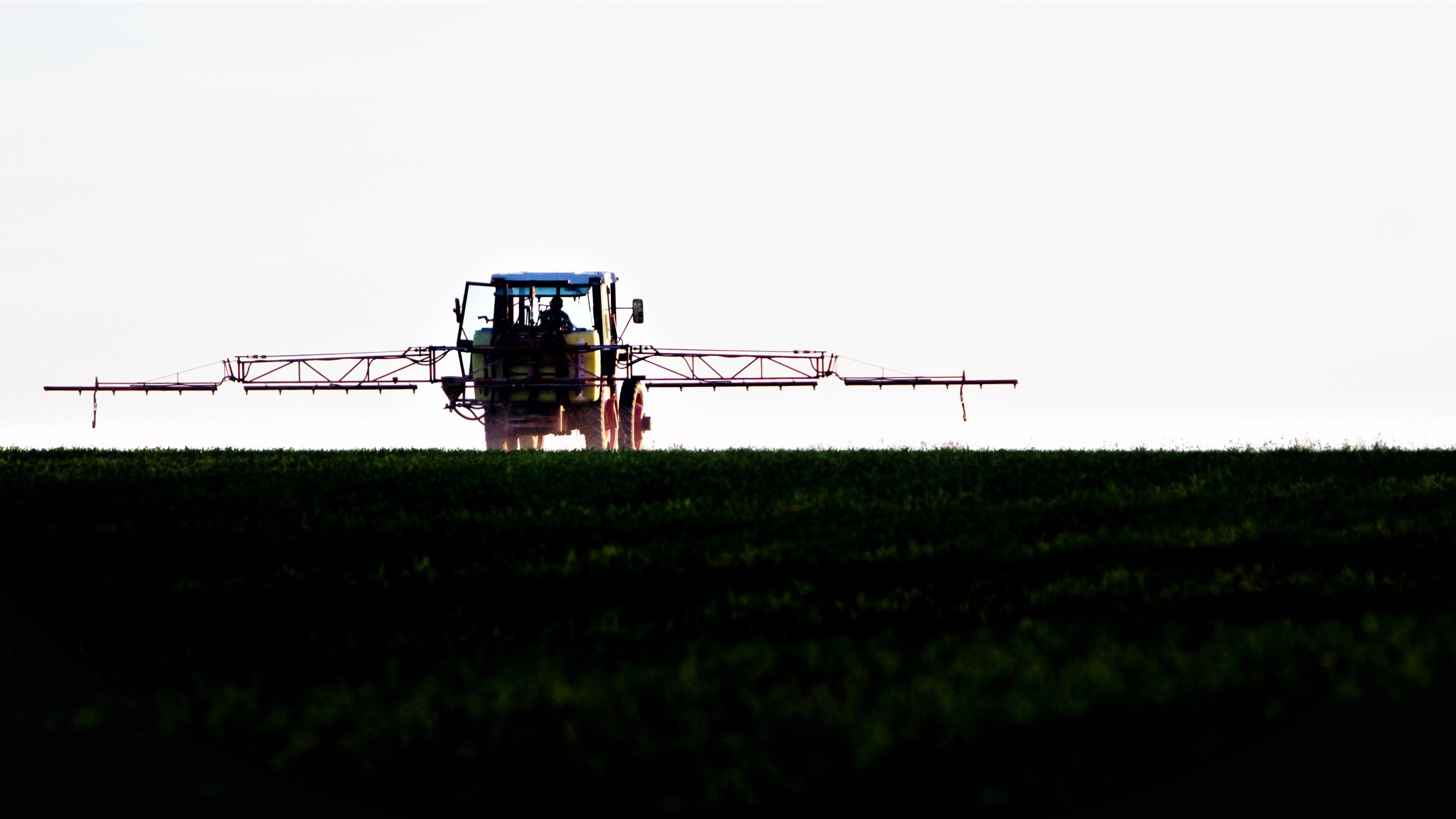En traktor kører over marken med en sprøjte