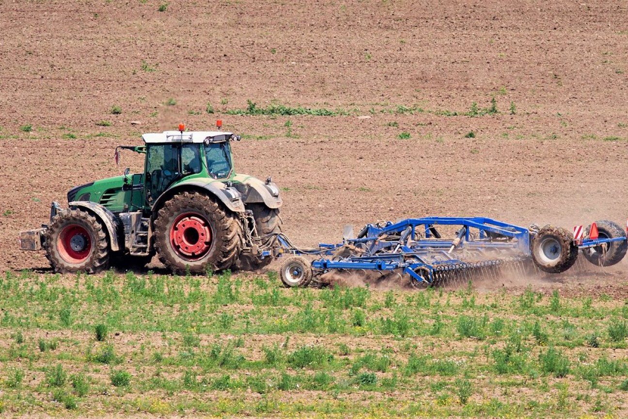 En traktor kører på en mark og harver
