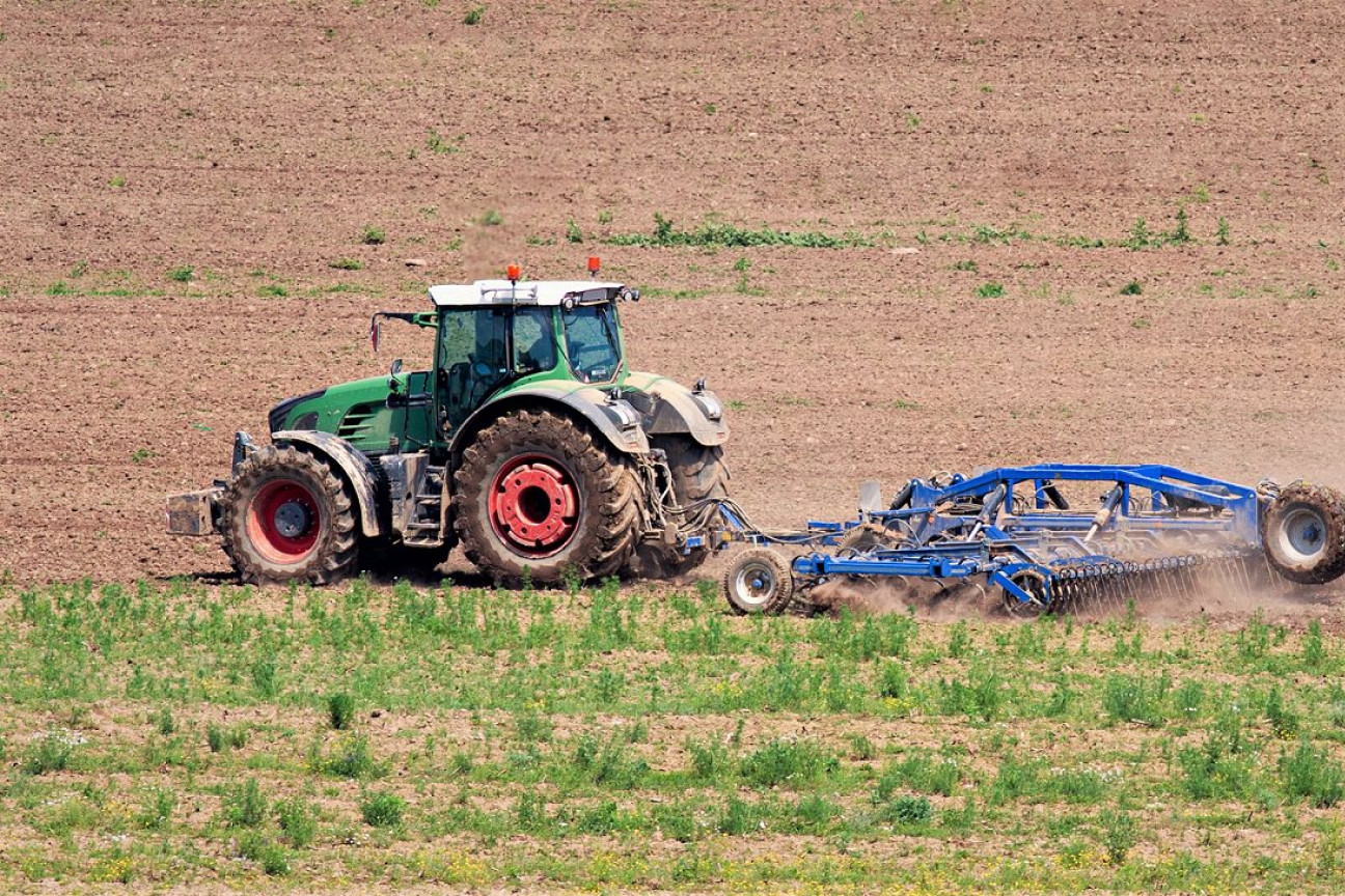 En traktor kører på en mark og harver