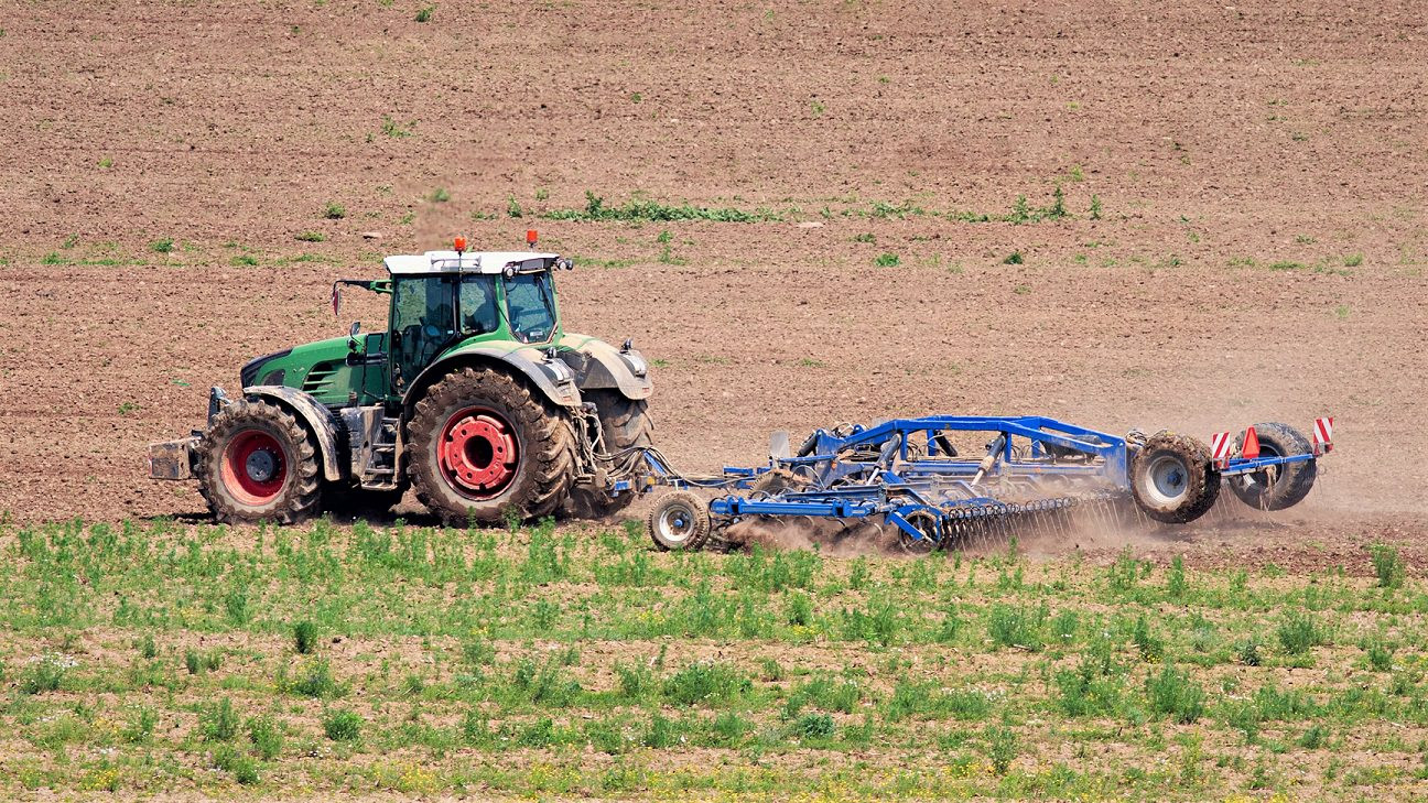 En traktor kører på en mark og harver