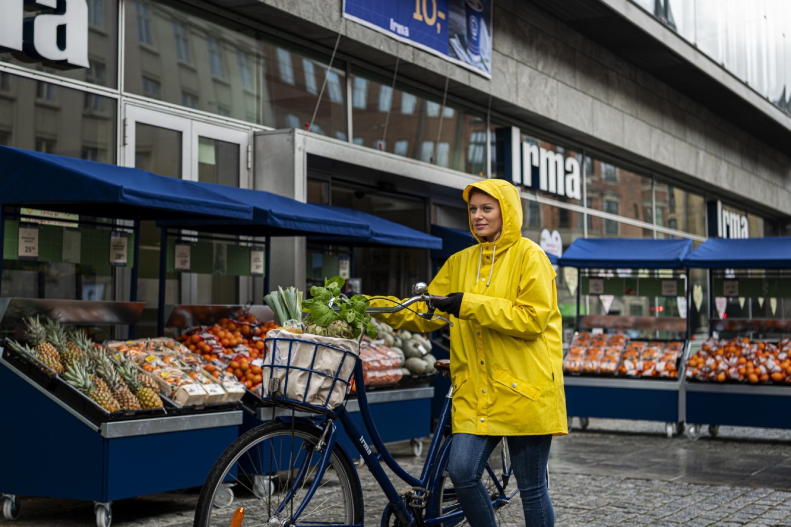 Kunde trækker cykel med fyldt cykelkurv foran Irma-butik.