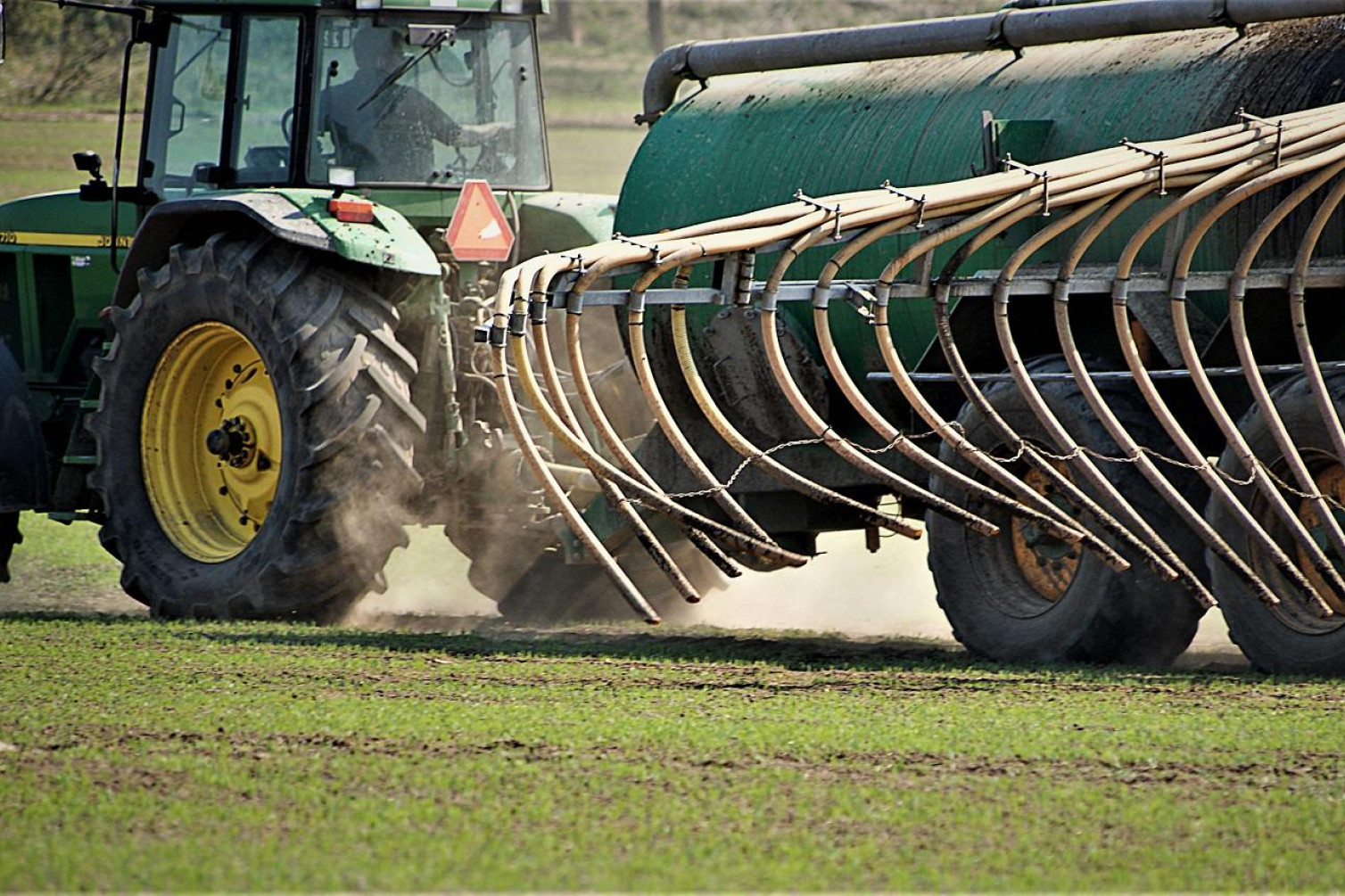 En traktor spreder gødning på marken