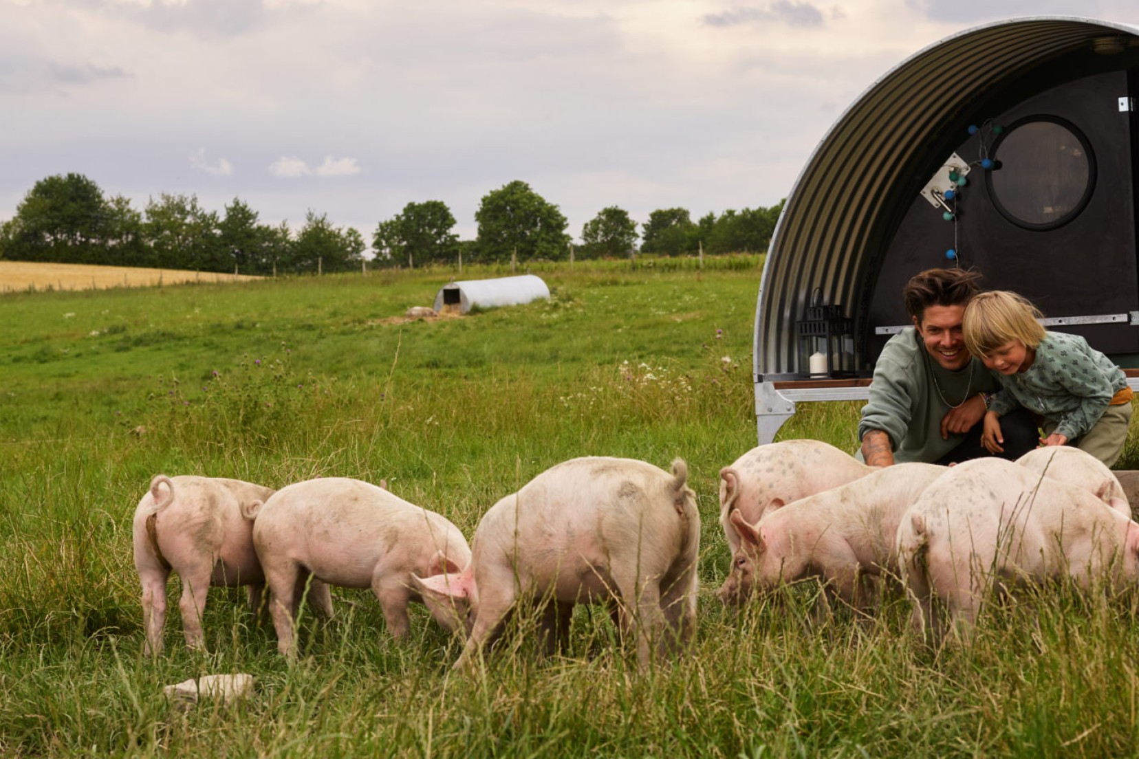 Gæster kæler med grise foran 'grisehytten'.