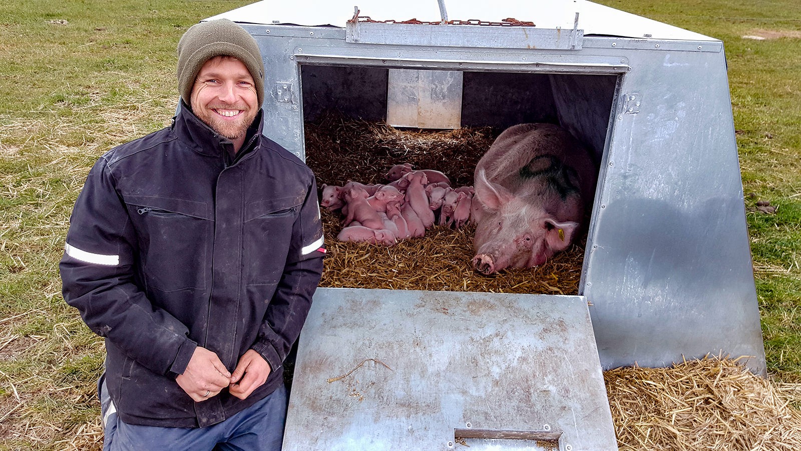 Per Midtgaard Olsen foran grisehytte med smågrise