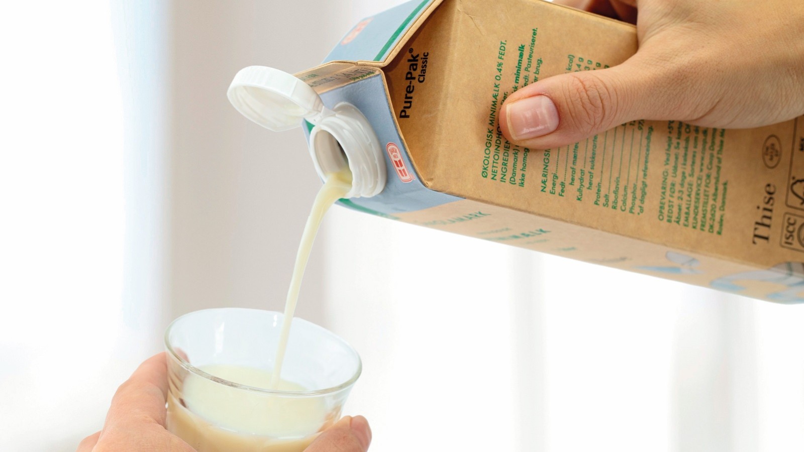 Mælk hælde fra karton til glas.