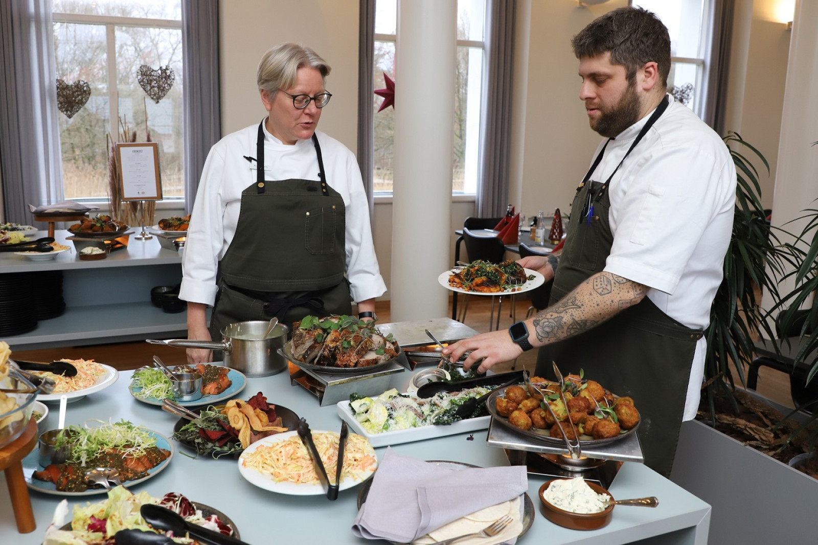 Køkkenchef Benedikte Overby, og souschef Rasmus Kristensen anretter de de sidste fade, inden dagens gæster myldrer ind til frokostbuffeten