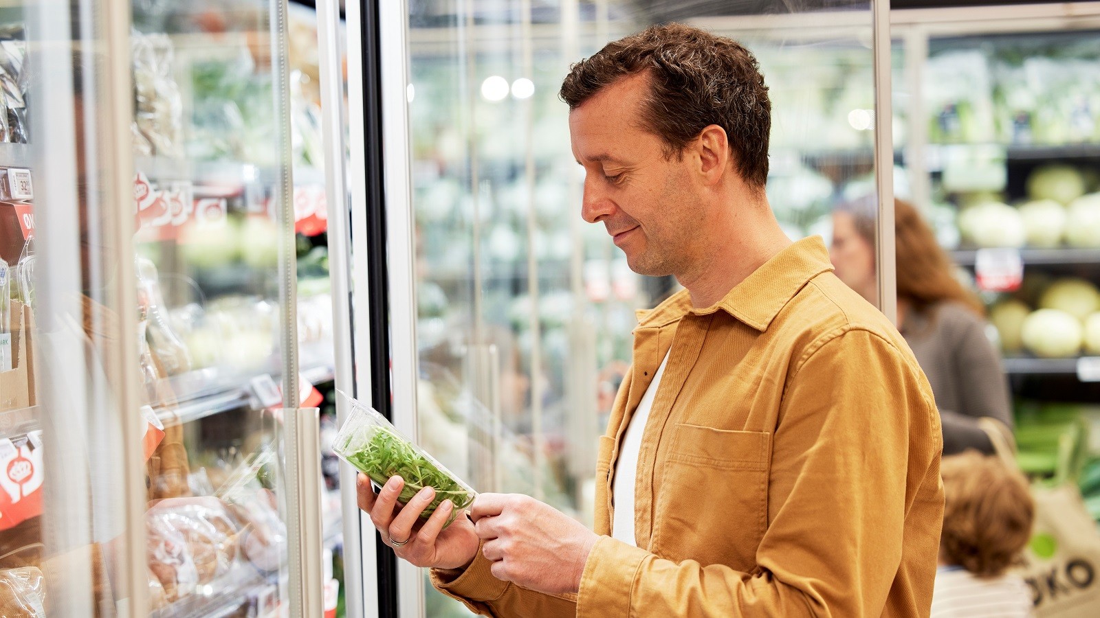Kunde kigger på pose med salat i butik.