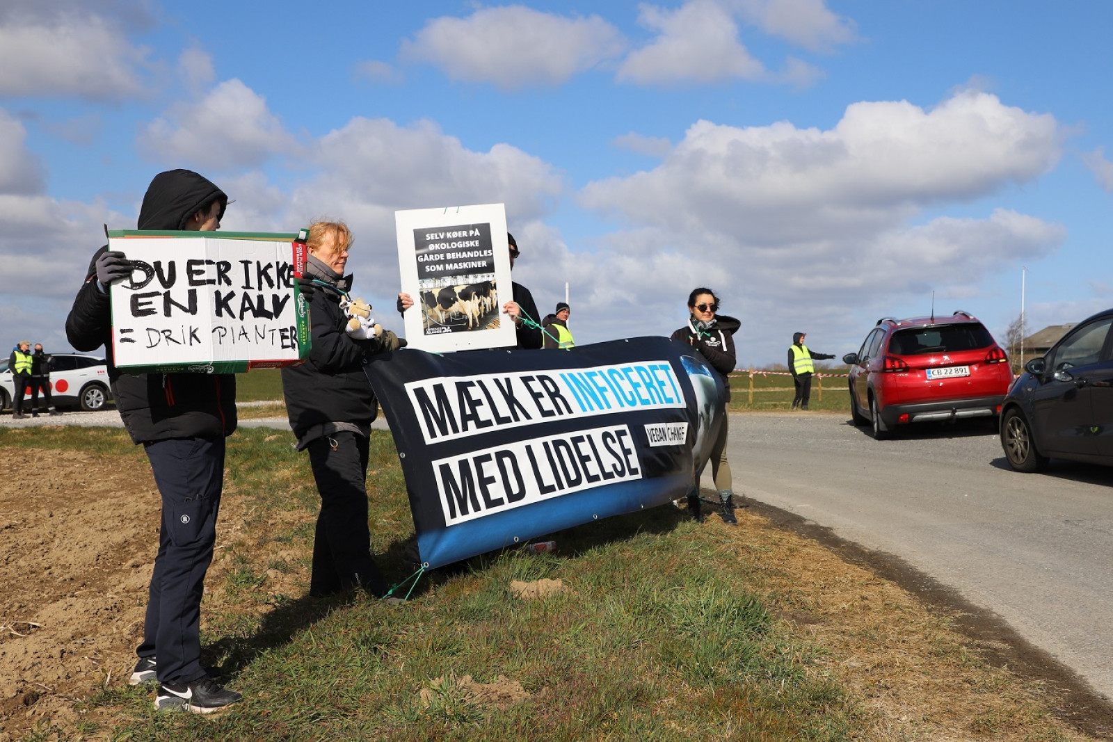 Aktivister fra Dyrenes Alliance med skilte og banner foran indkørslen til Heegaard.