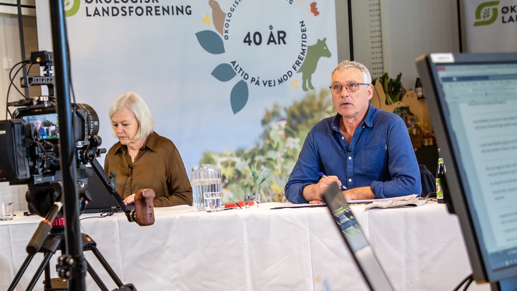 Per Kølster sidder ved siden af Kirsten Back-Holck og taler til et kamera ifm. foreningens generalforsamling