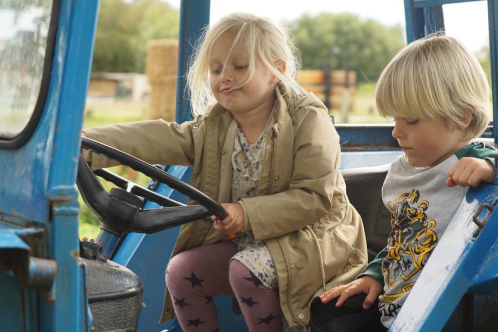 Silja og Elliott sidder i en blå traktor og leger