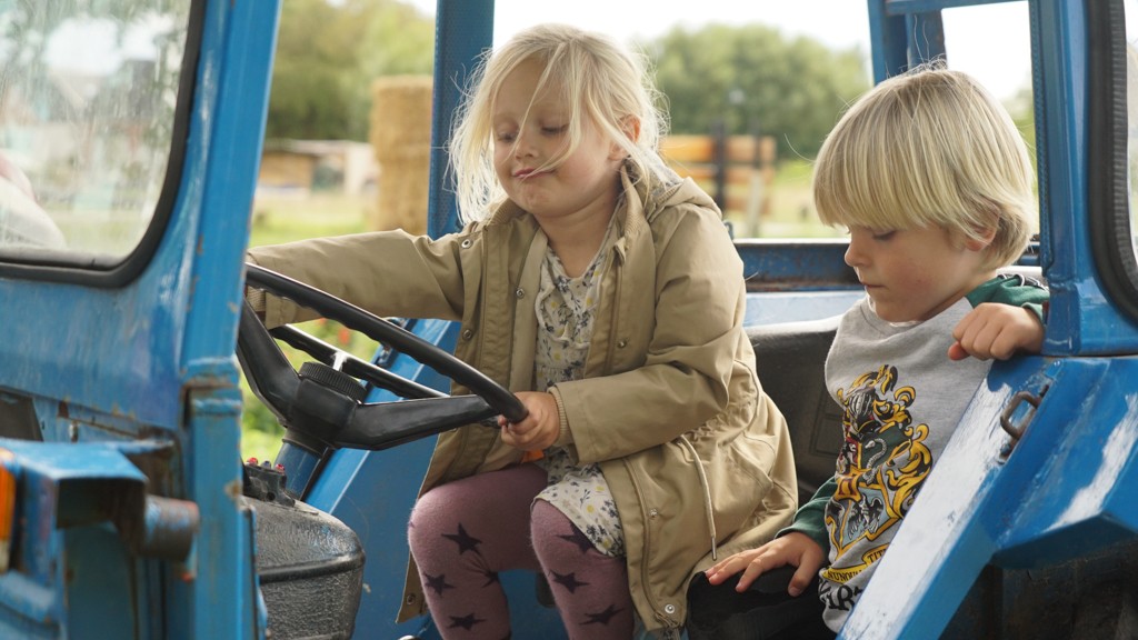 Silja og Elliott sidder i en blå traktor og leger