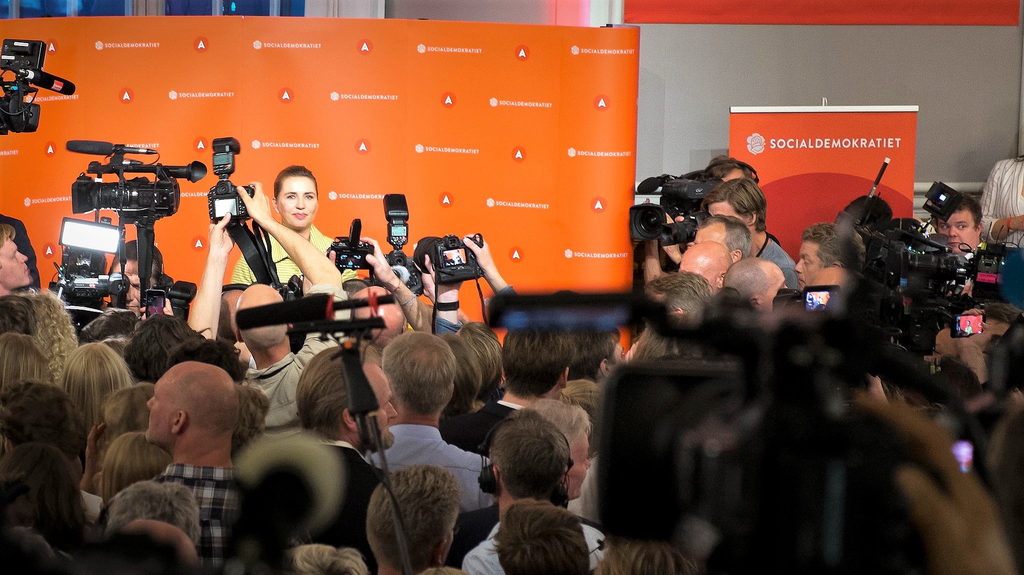 En masse fotografer står samlet og tager billeder af Mette Frederiksen