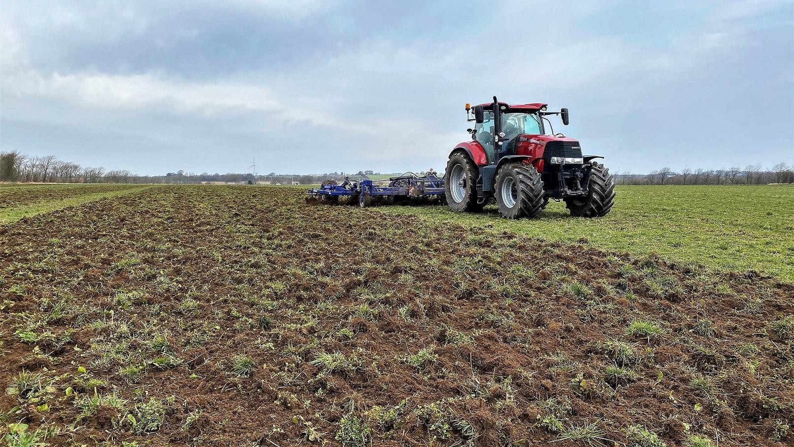 En traktor kører hen over en græsmark