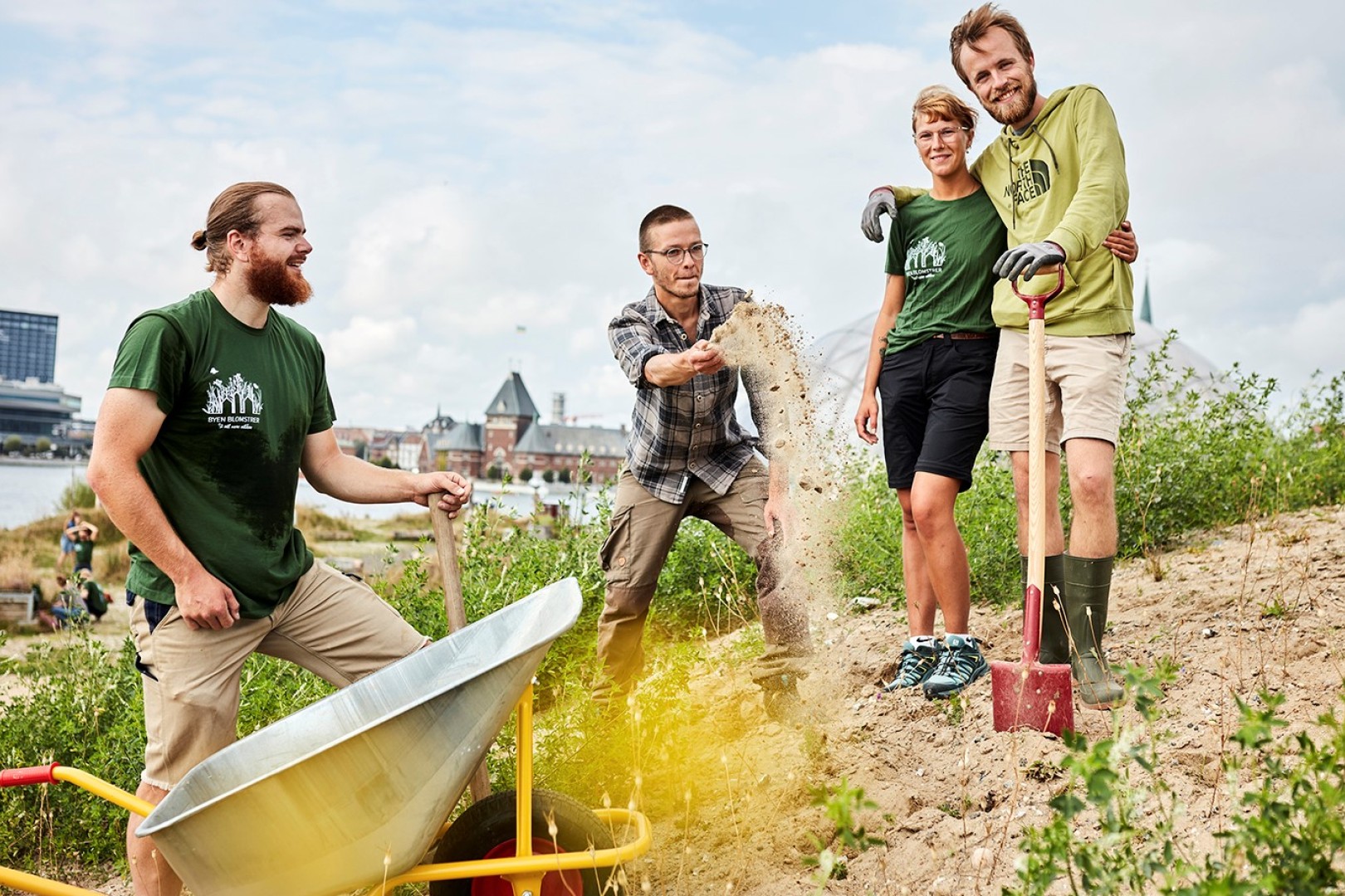Fire unge står nær Aarhus Havn i arbejdstøj og arbejder på at så blomster og planter