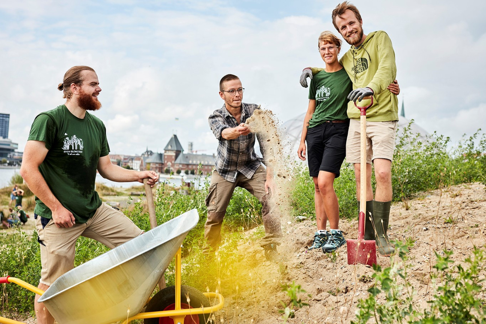 Fire unge står nær Aarhus Havn i arbejdstøj og arbejder på at så blomster og planter
