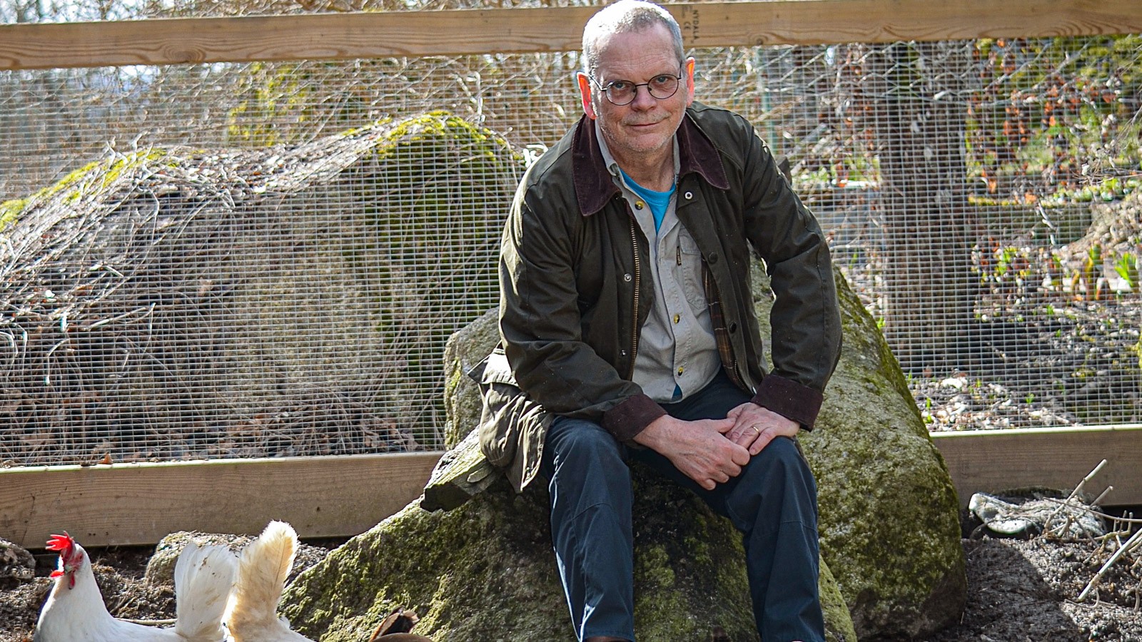 Per Jensen sidder i sin hønsegård med høns omkring sig