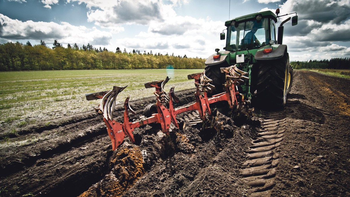 Nærbillede af en traktor, der pløjer jorden