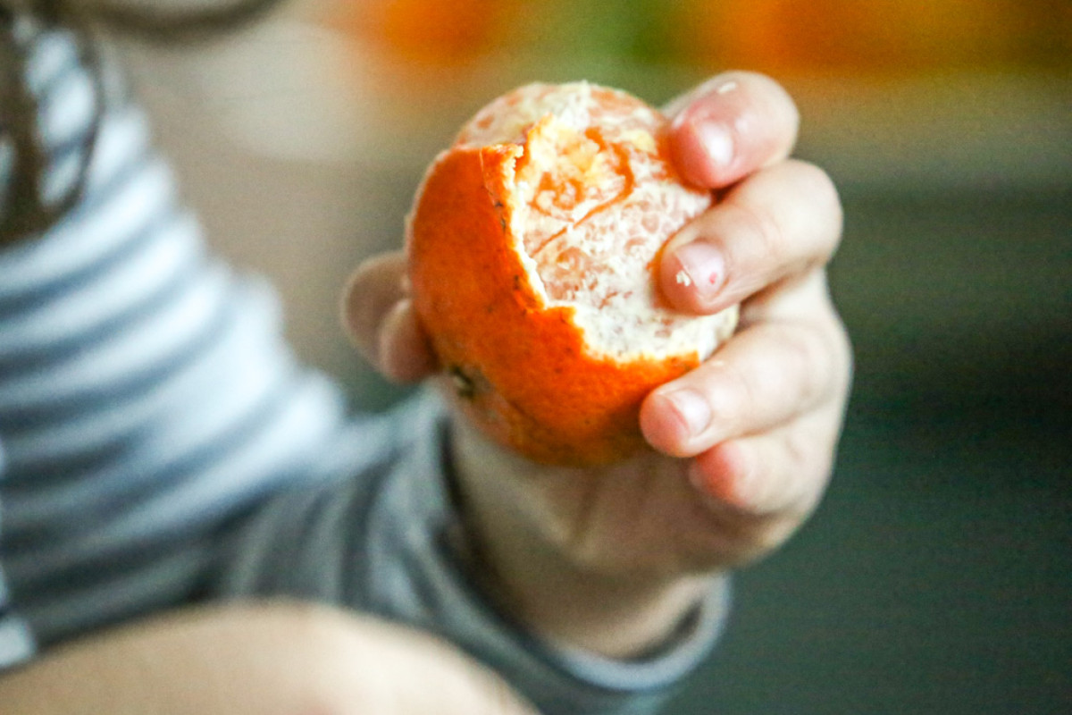 Et barn er ved at skrælle en appelsin