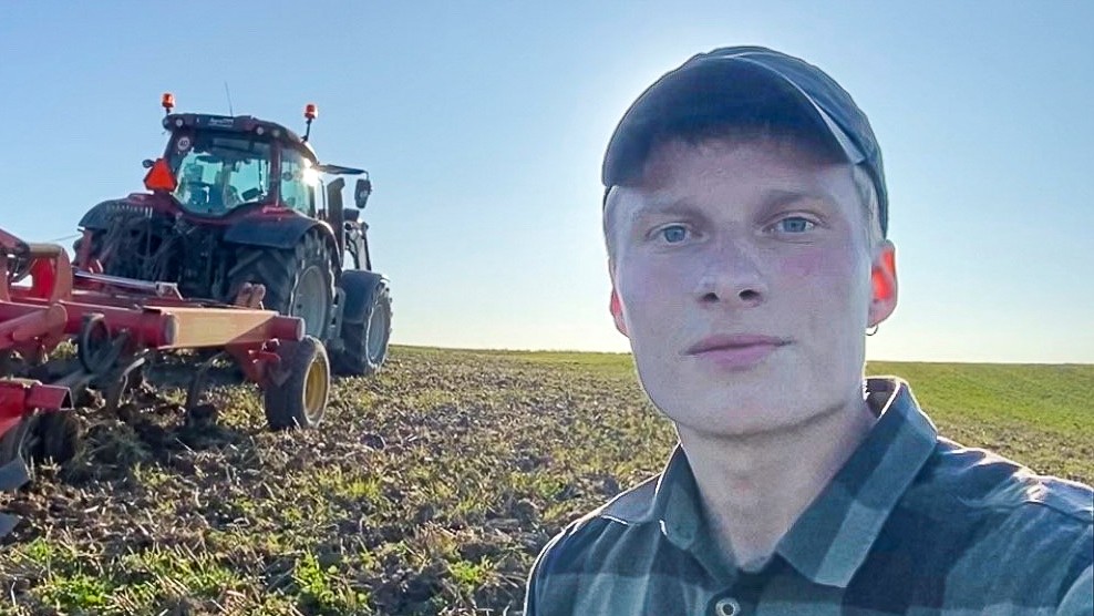 Victor Leth står i marken med en traktor bag sig