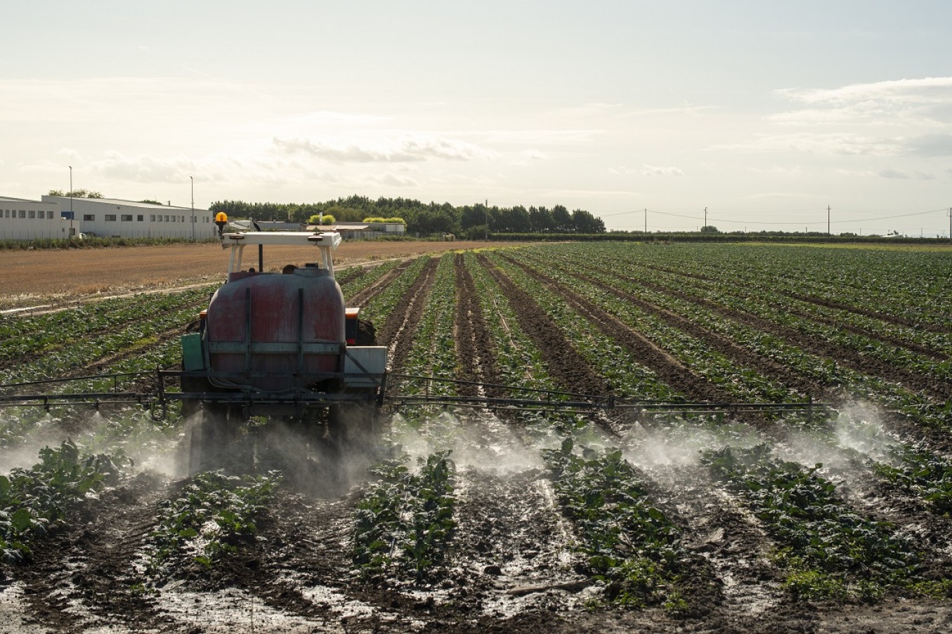 En traktor spreder pesticider på en mark