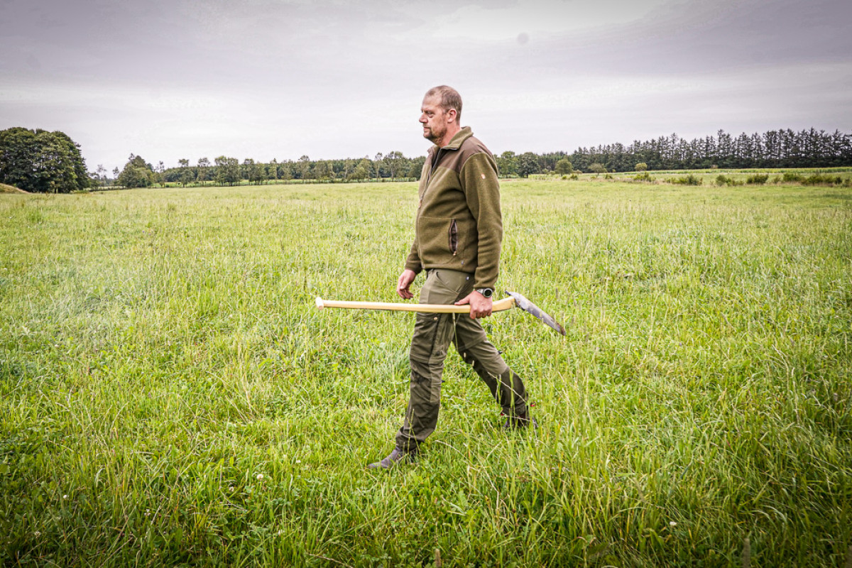 Gert går over en græsmark med en spade i hånden