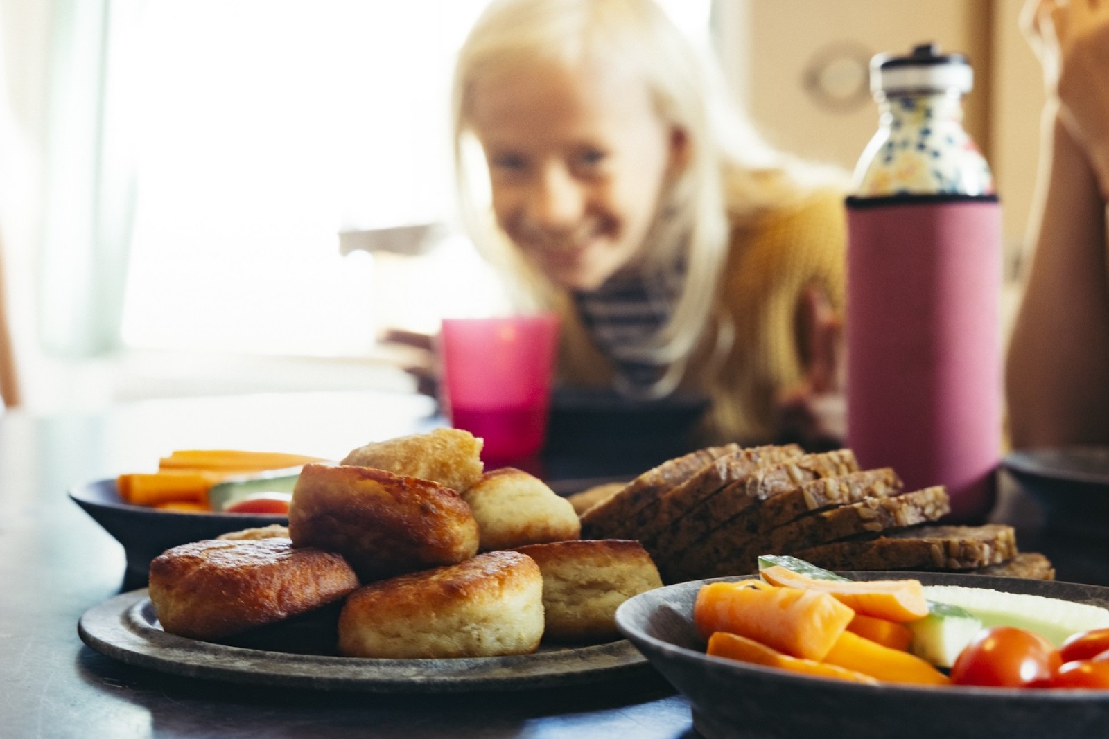 Gnavefrugt, fiskefrikadeller og lunt rugbrød på bordet foran skoleelever