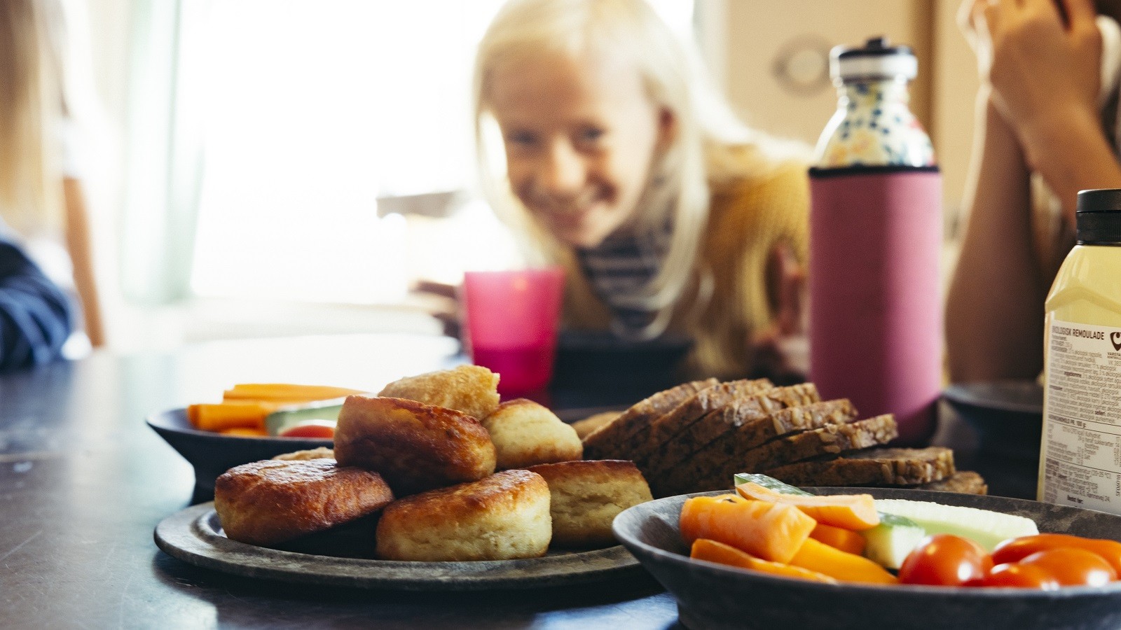 Gnavefrugt, fiskefrikadeller og lunt rugbrød på bordet foran skoleelever