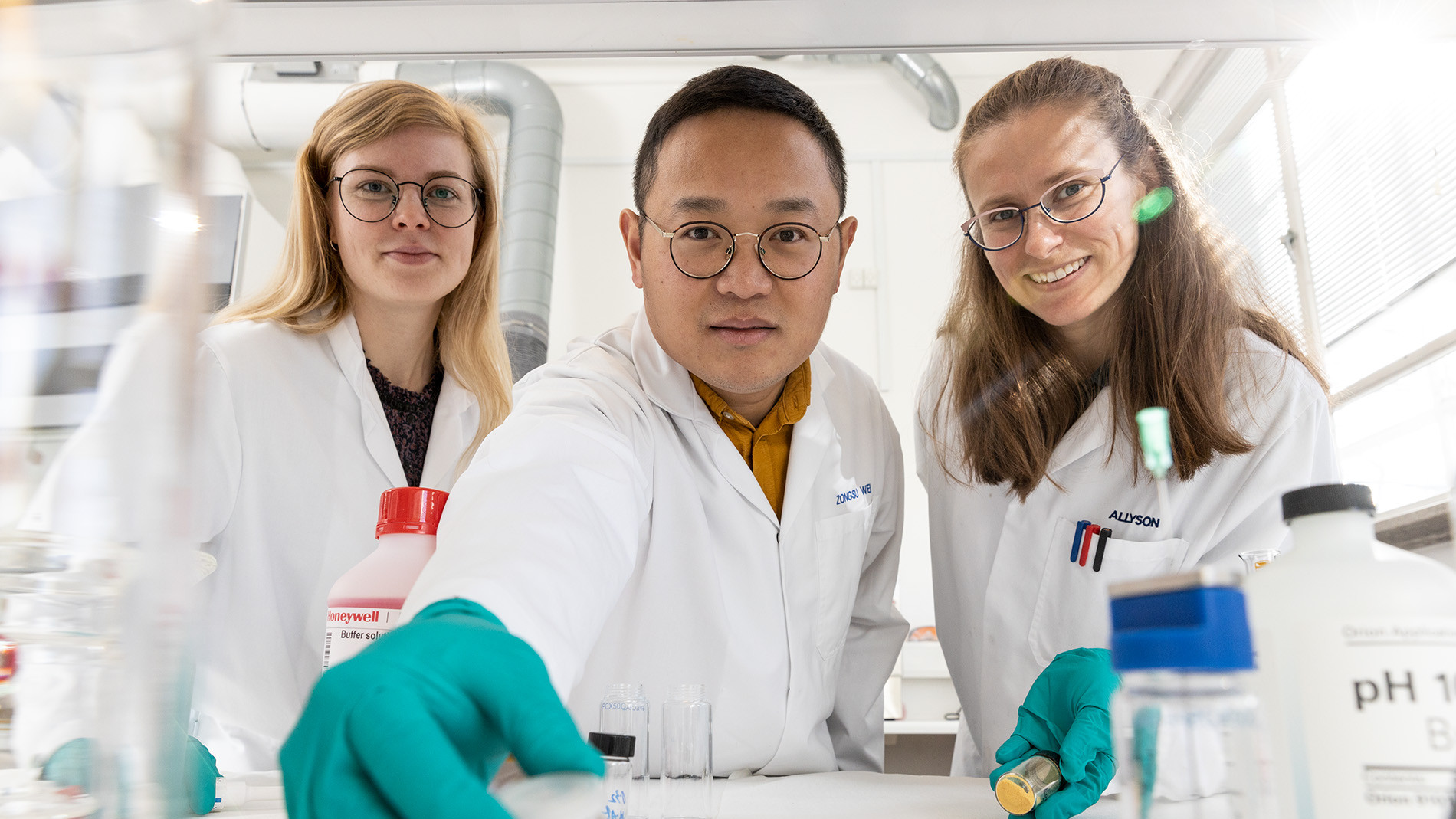 Ph.d.-studerende Charlotte Skjold Qvist Christensen (t.v.), adjunkt Zongsu Wei (midt) og ph.d.-studerende Allyson Leigh Junker står ved siden af hinanden i et laboratorium