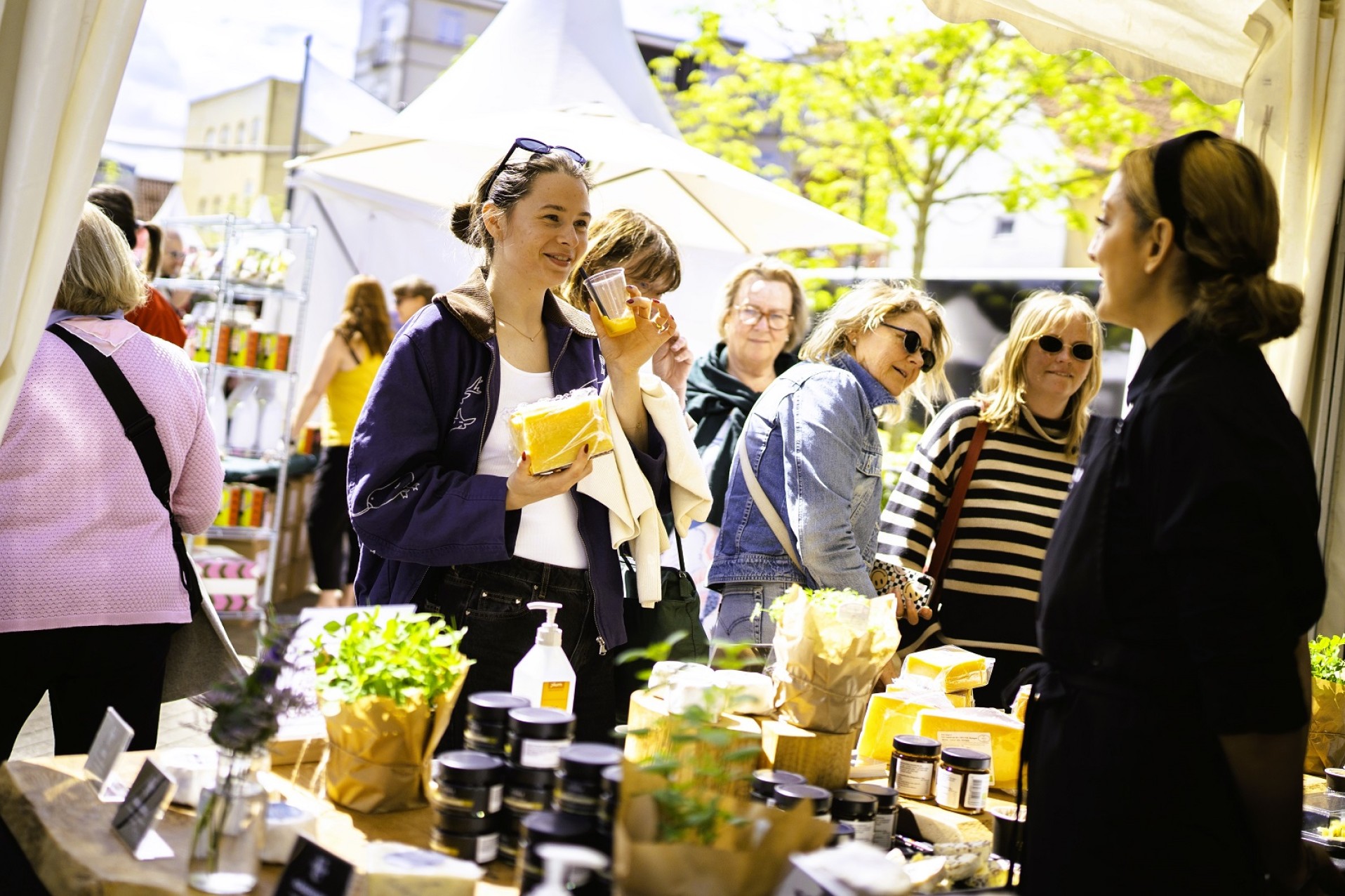En kvinde smager på en drik ved en stand på Madens Folkemøde