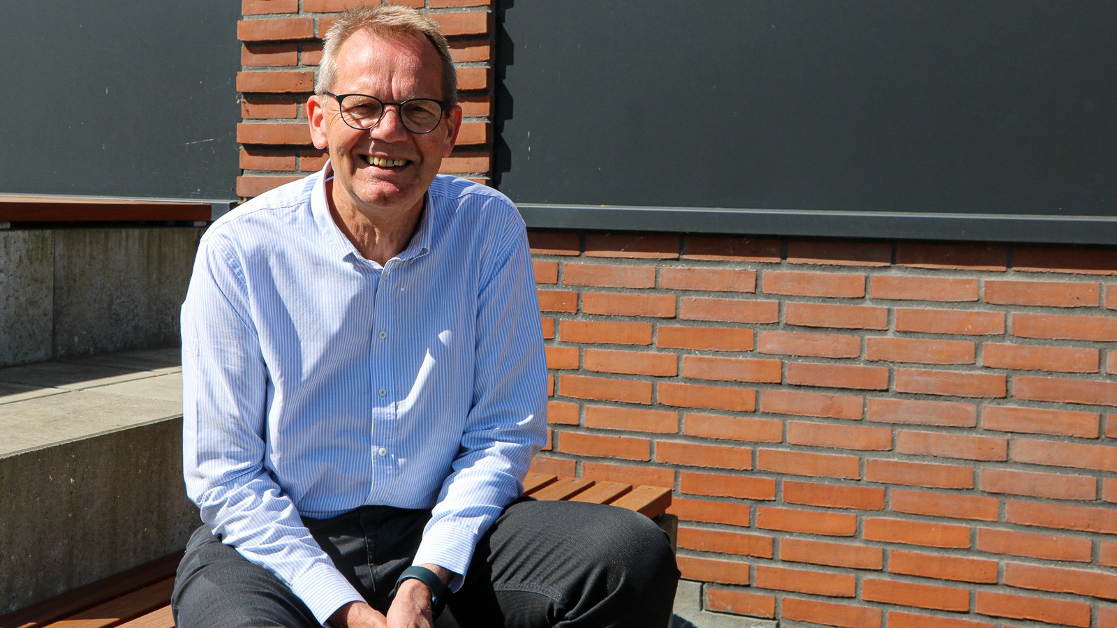 Peder Bligaard sidder i solen og smiler til kameraet