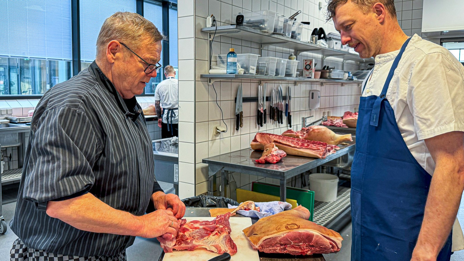 Det er den pensionerede slagter og kok John Rasmussen t.v., som underviser kunderne i, hvordan de udskærer naturgrisene. Her besøger han bistroen i Bankdata i Silkeborg, hvor køkkenchef Mads Henriksen Birk ser flere fordele ved at modtage hele dyr