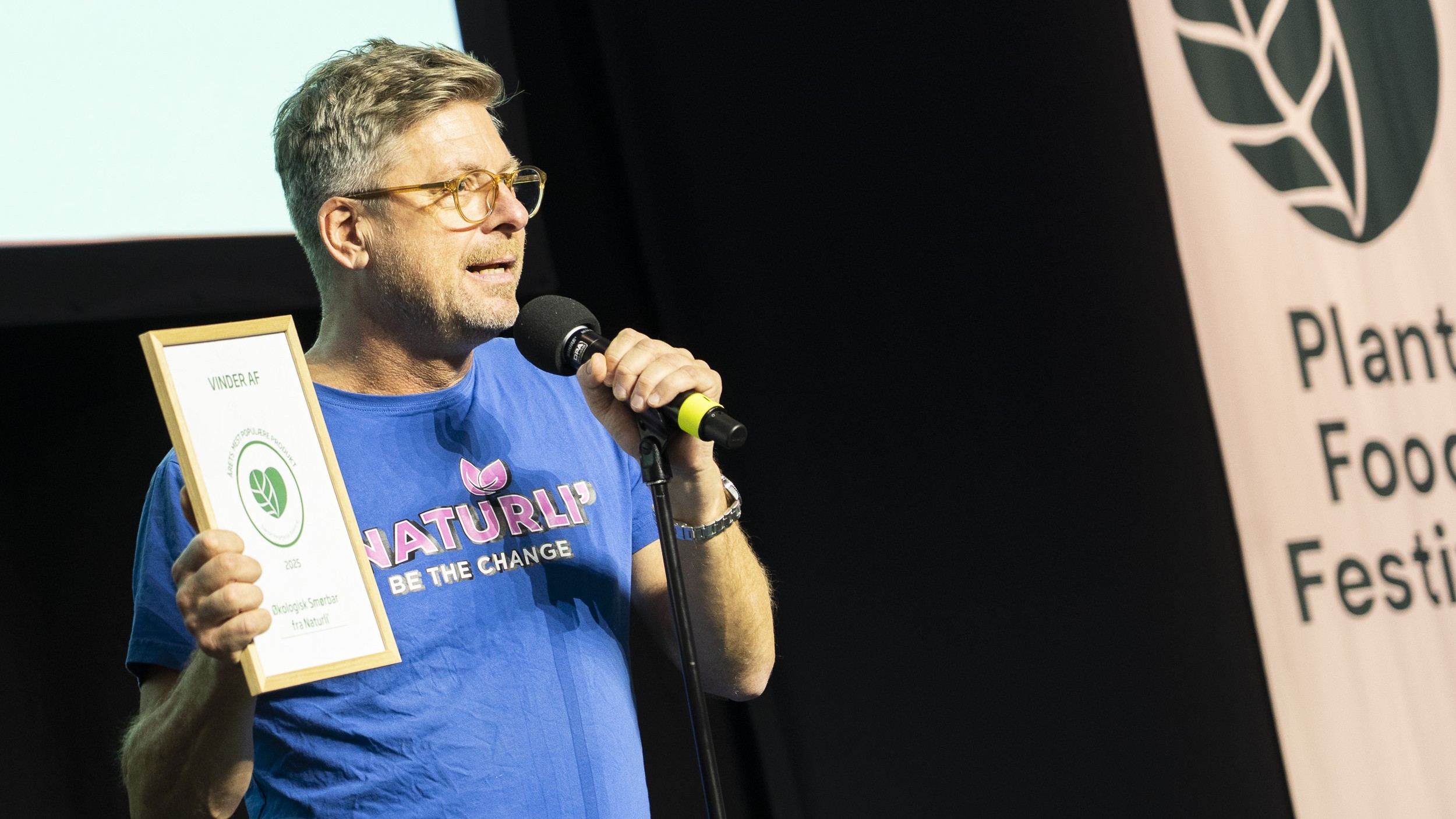 Henrik Lund taler i en mikrofon og holder diplomet op efter at have vundet prisen for årets plantebaserede produkt med Smørbar
