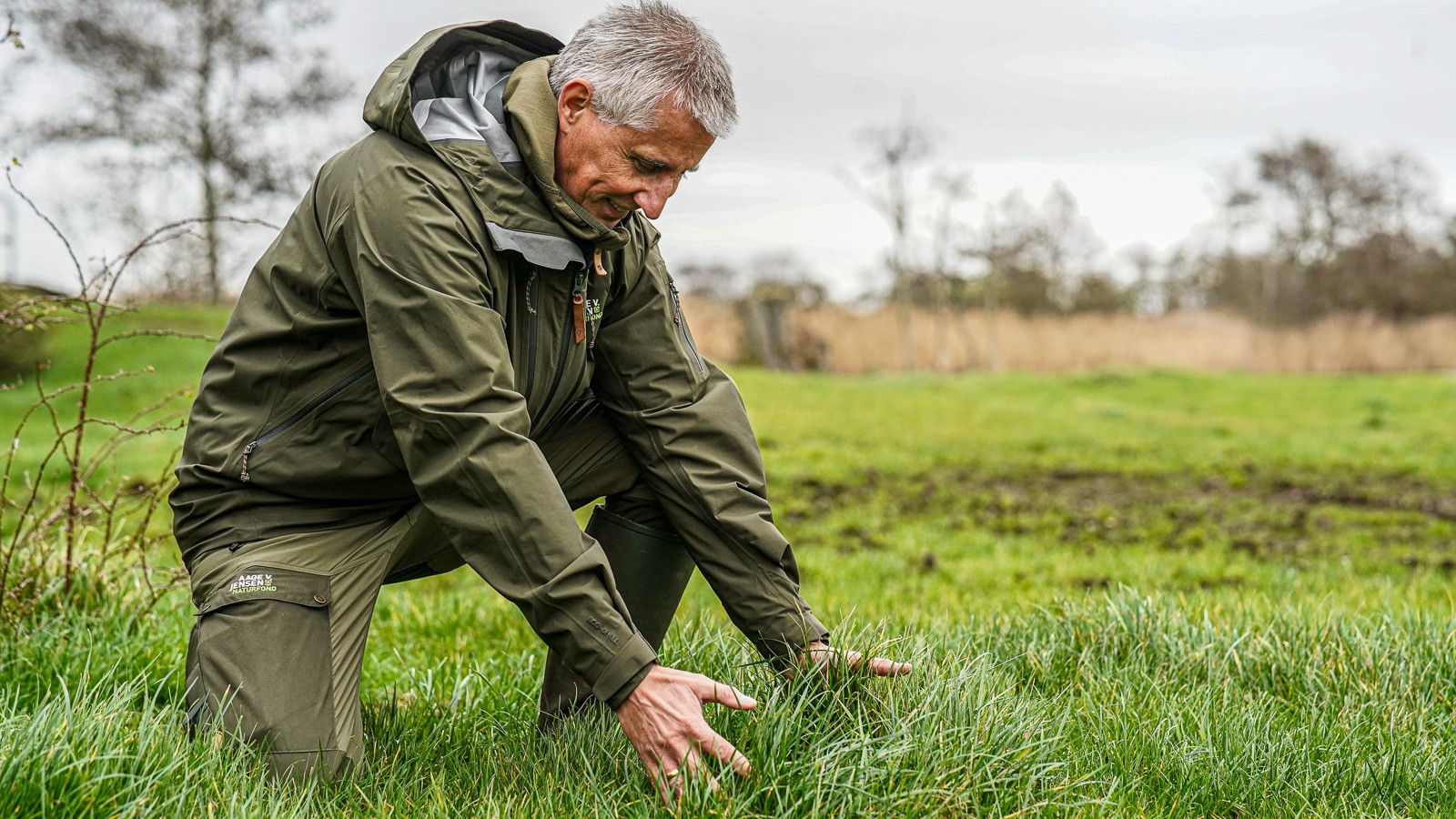 Niels Dahlin Lisborg sidder på et knæ og griber ud efter græsstrå